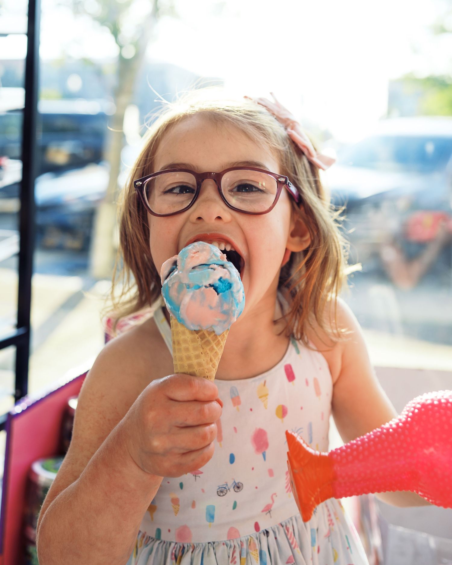 Joyful expression while eating bright blue ice cream from a waffle cone.