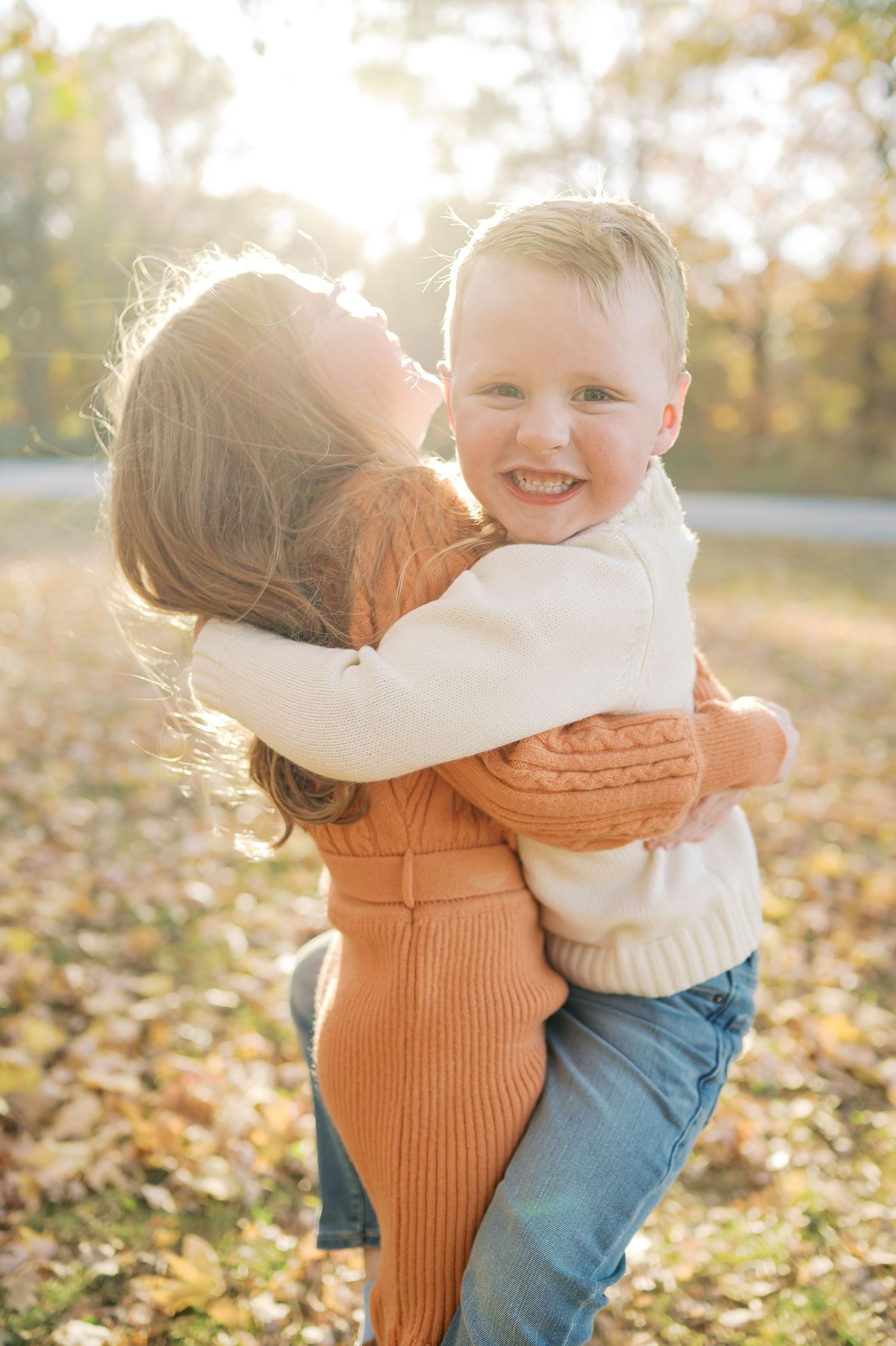Joyful interaction captured in warm autumn lighting with orange sweater and white knit details.