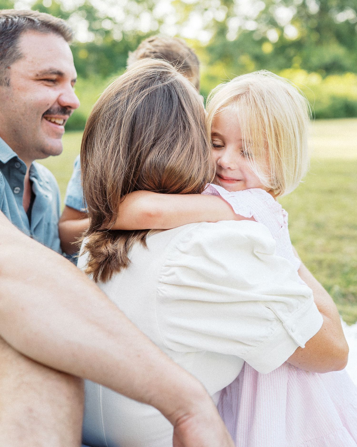 A tender family embrace captured outdoors during a summer photoshoot.