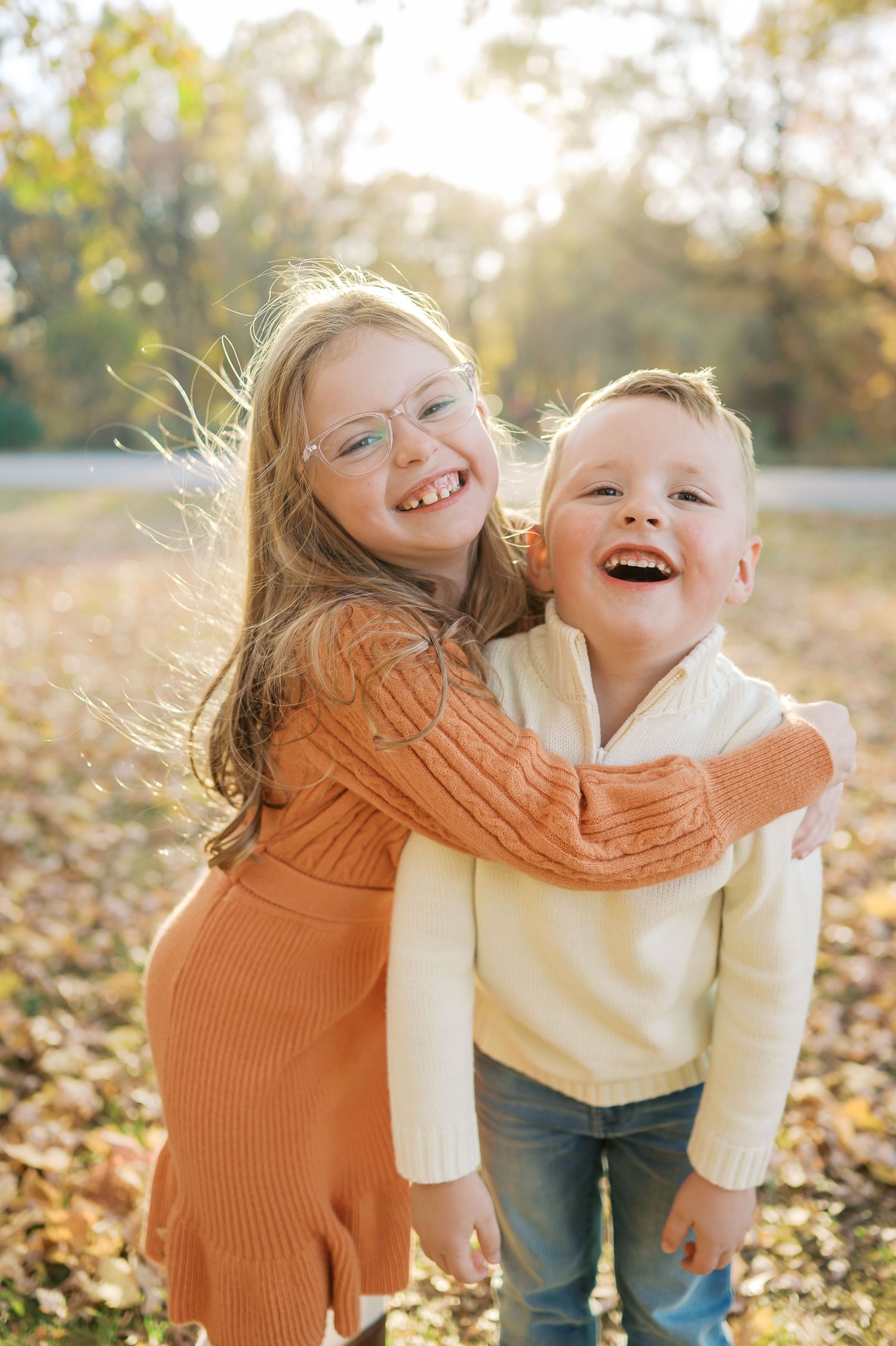 Candid laughter and embraces captured in golden hour lighting among fallen autumn leaves.
