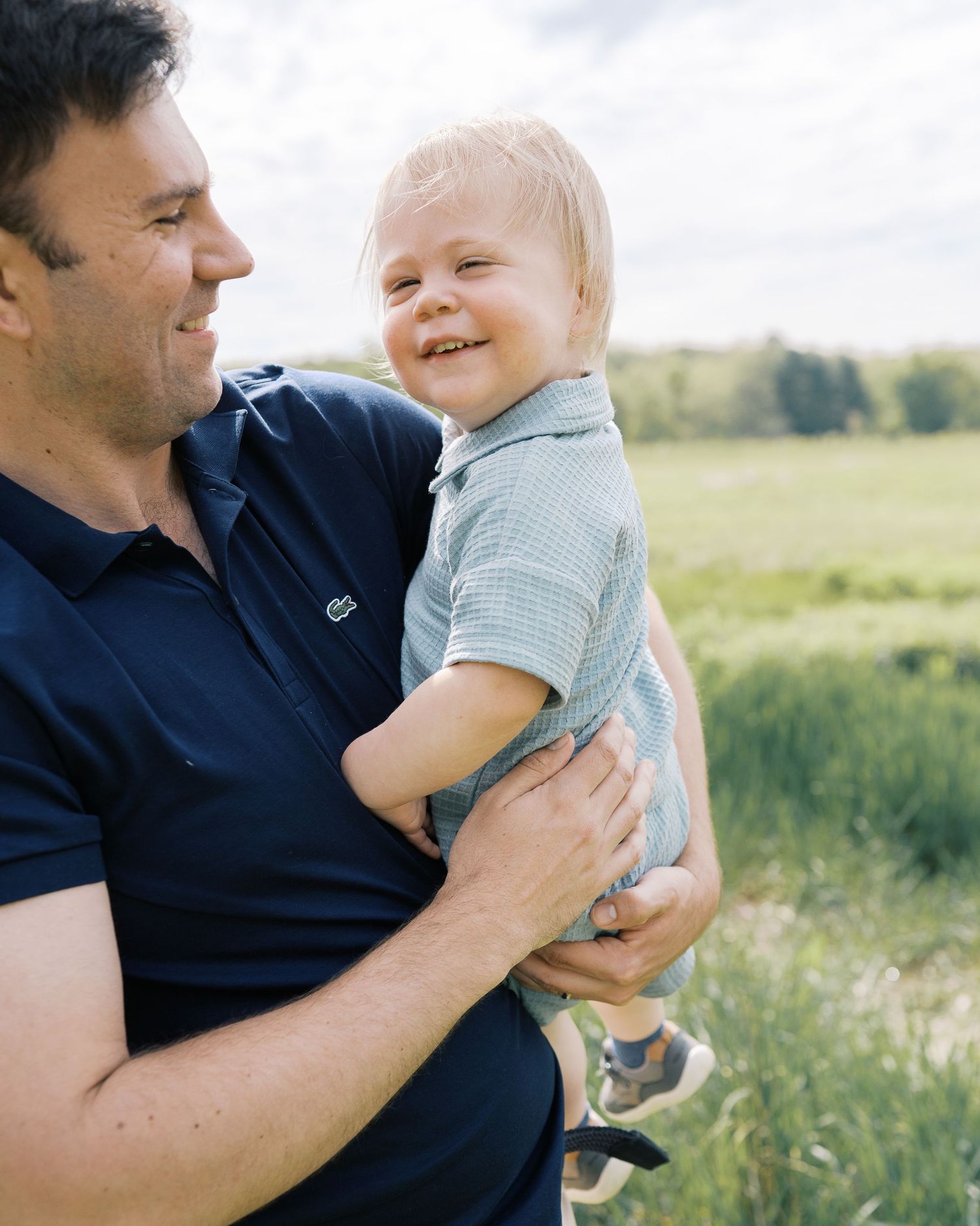 A joyful moment between parent and child in a summer field wearing blue shirts.