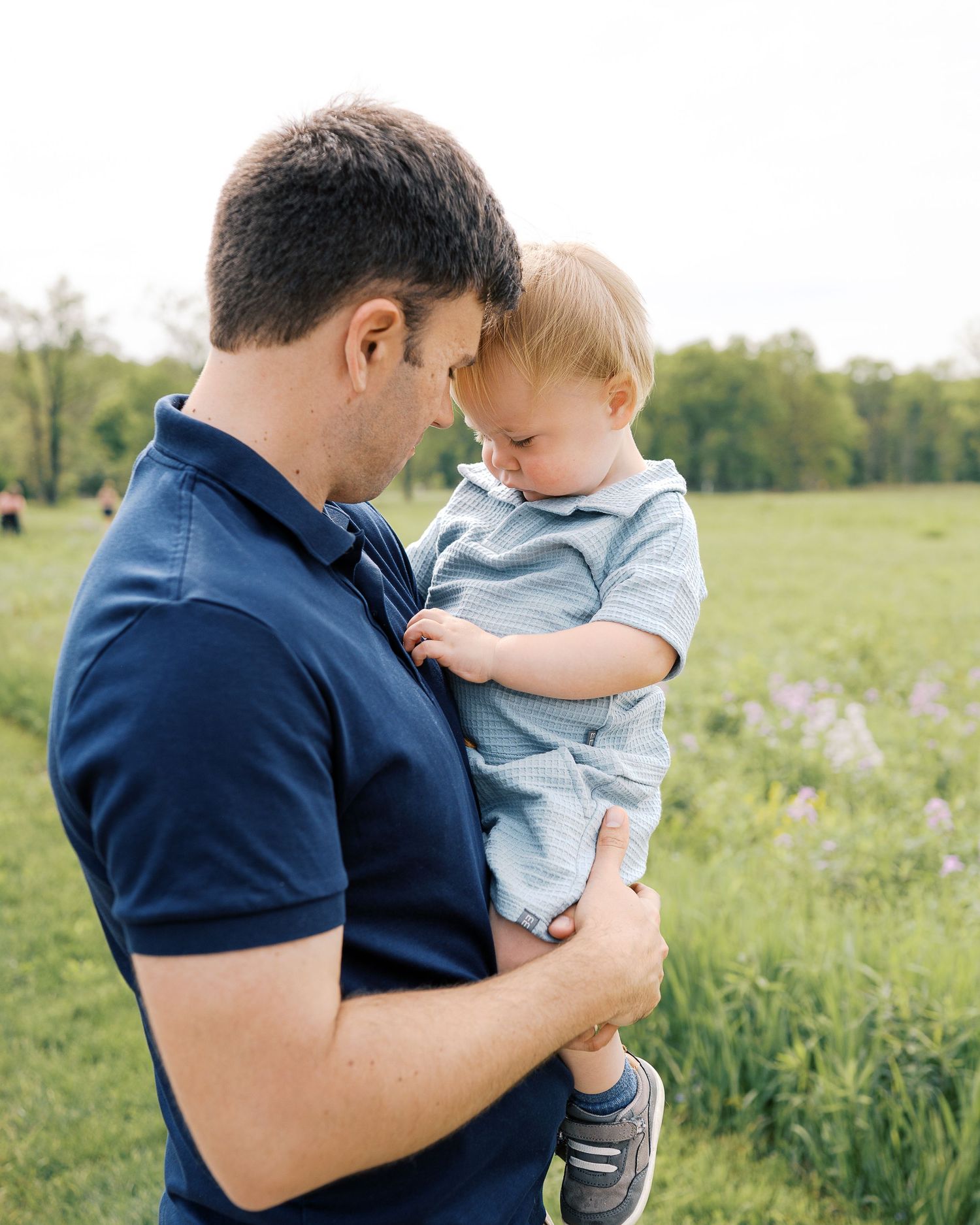 Natural outdoor family photo session with people wearing navy and light blue in a grassy field.
