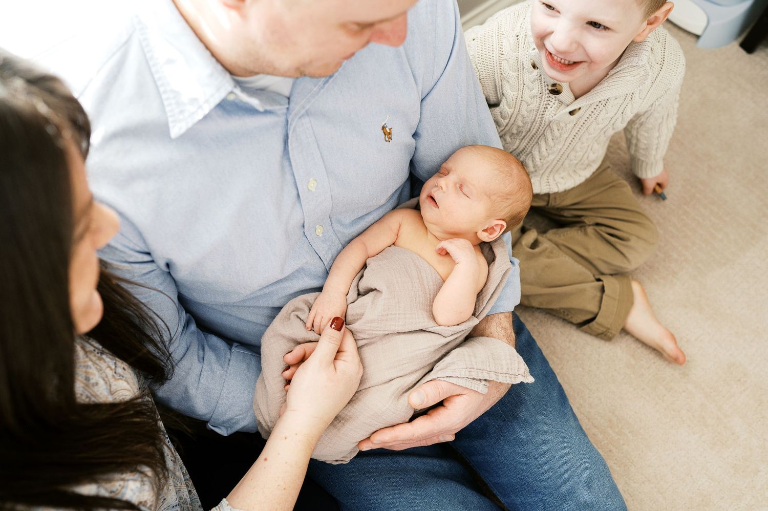 A family gathered on the floor shares an intimate moment with their newborn baby.