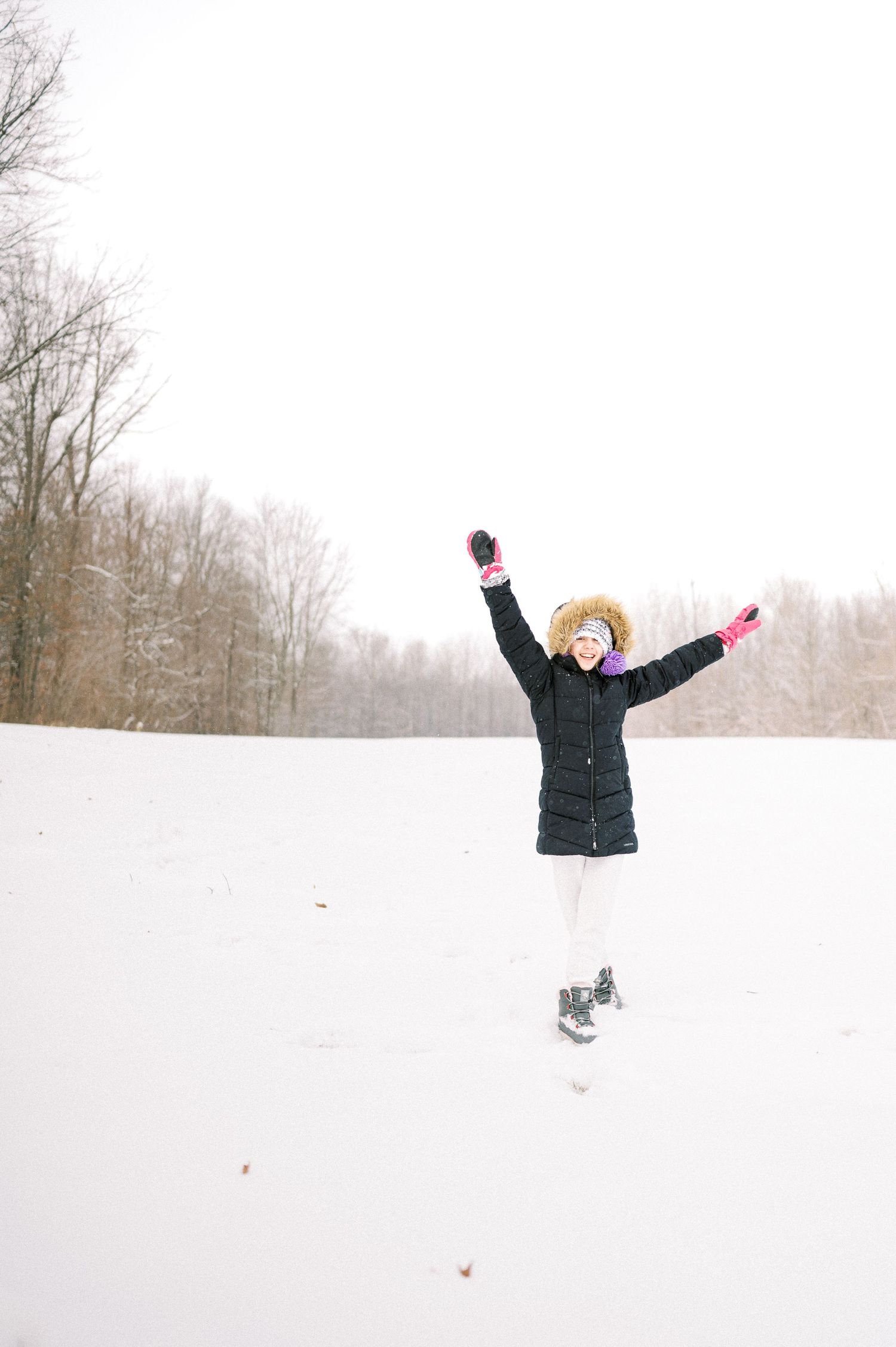 Someone leaping with outstretched arms in a snowy winter landscape.