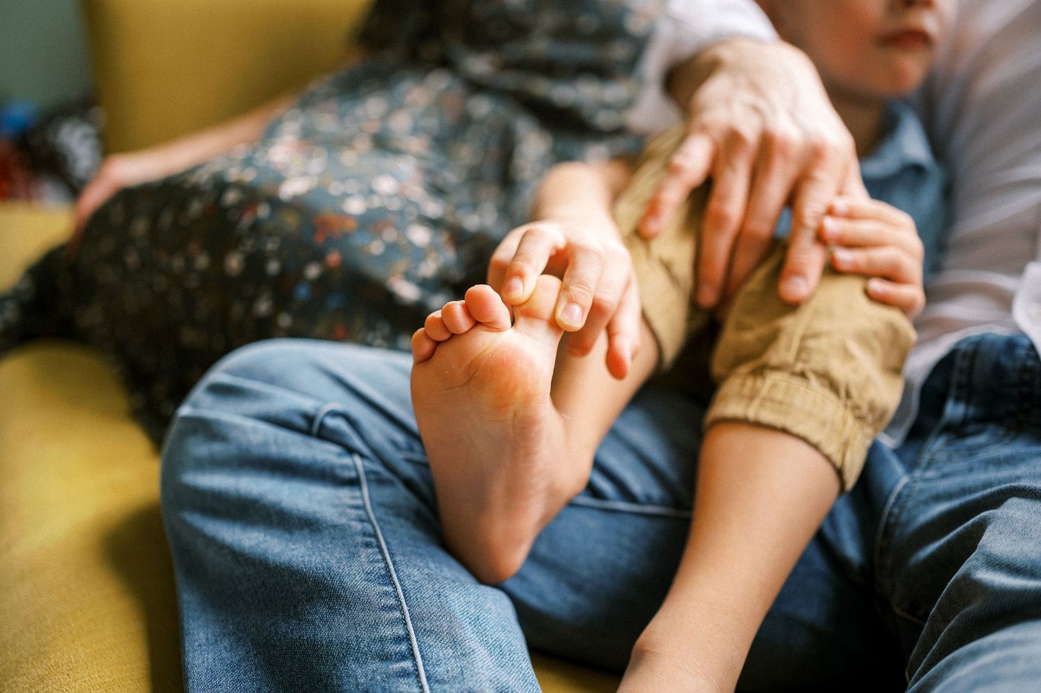Close-up detail of hands held in a tender moment on a couch.