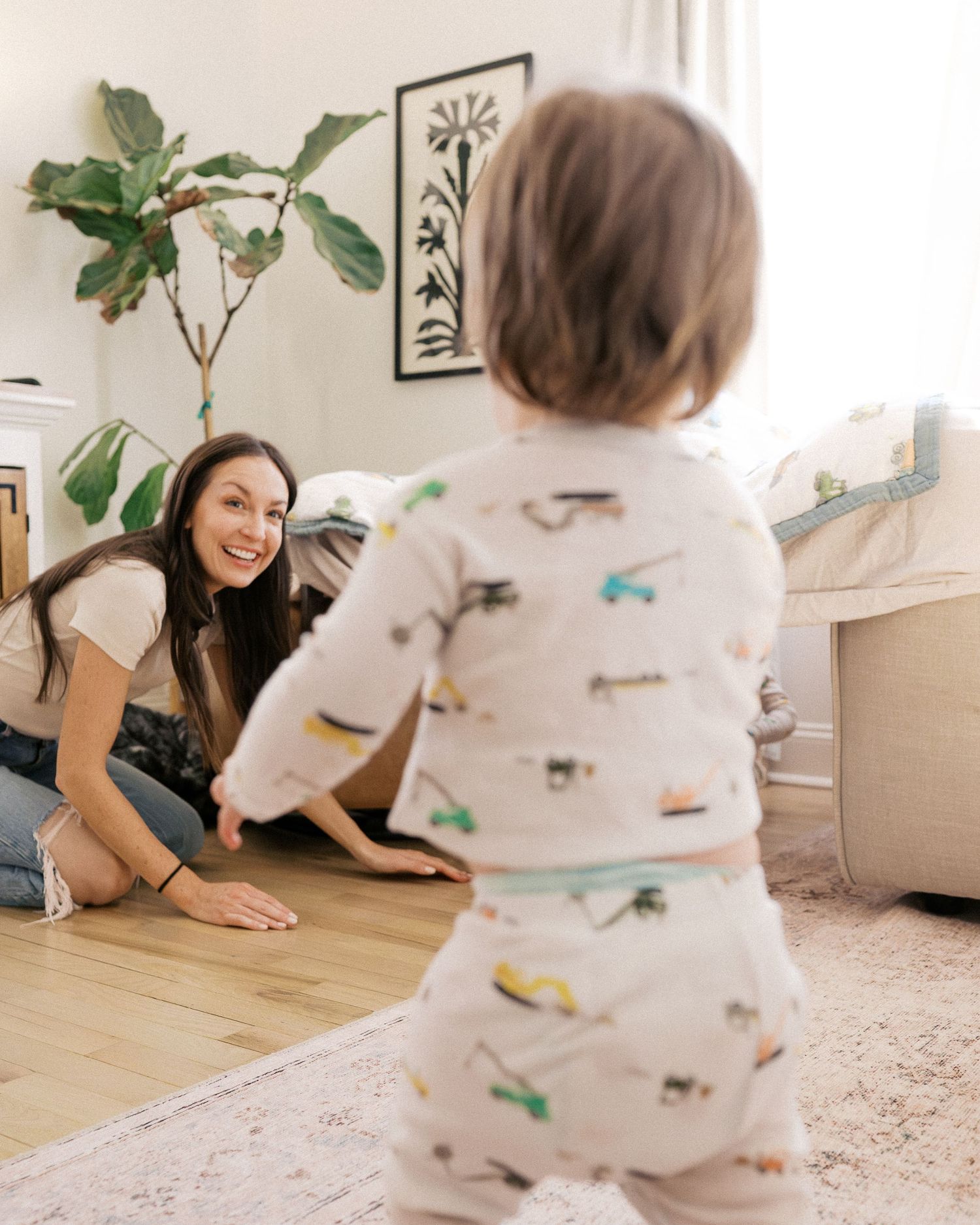 A playful moment of hide and seek in a sunlit living room with houseplants and wall art.