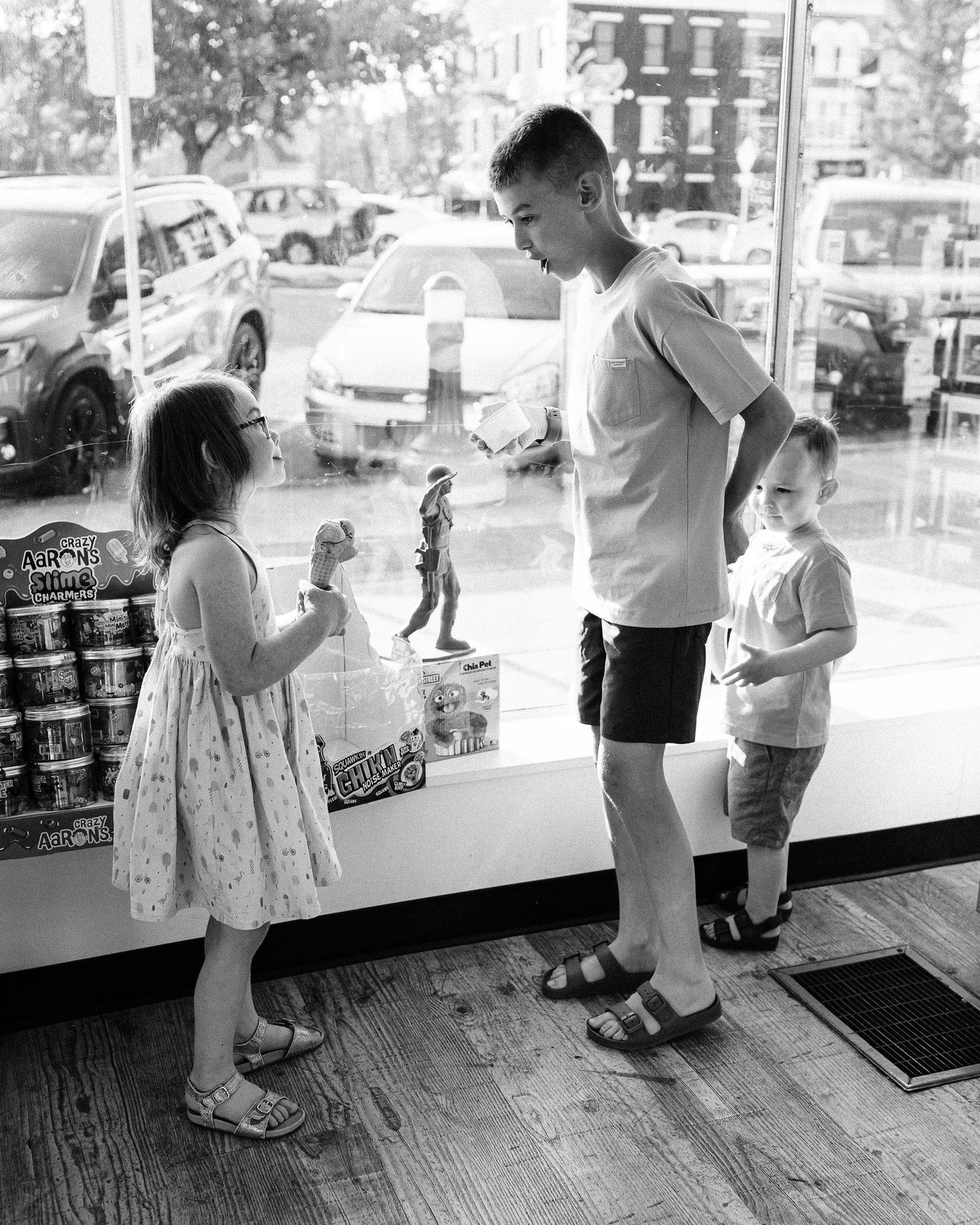 Black and white image of people interacting in an ice cream shop interior.