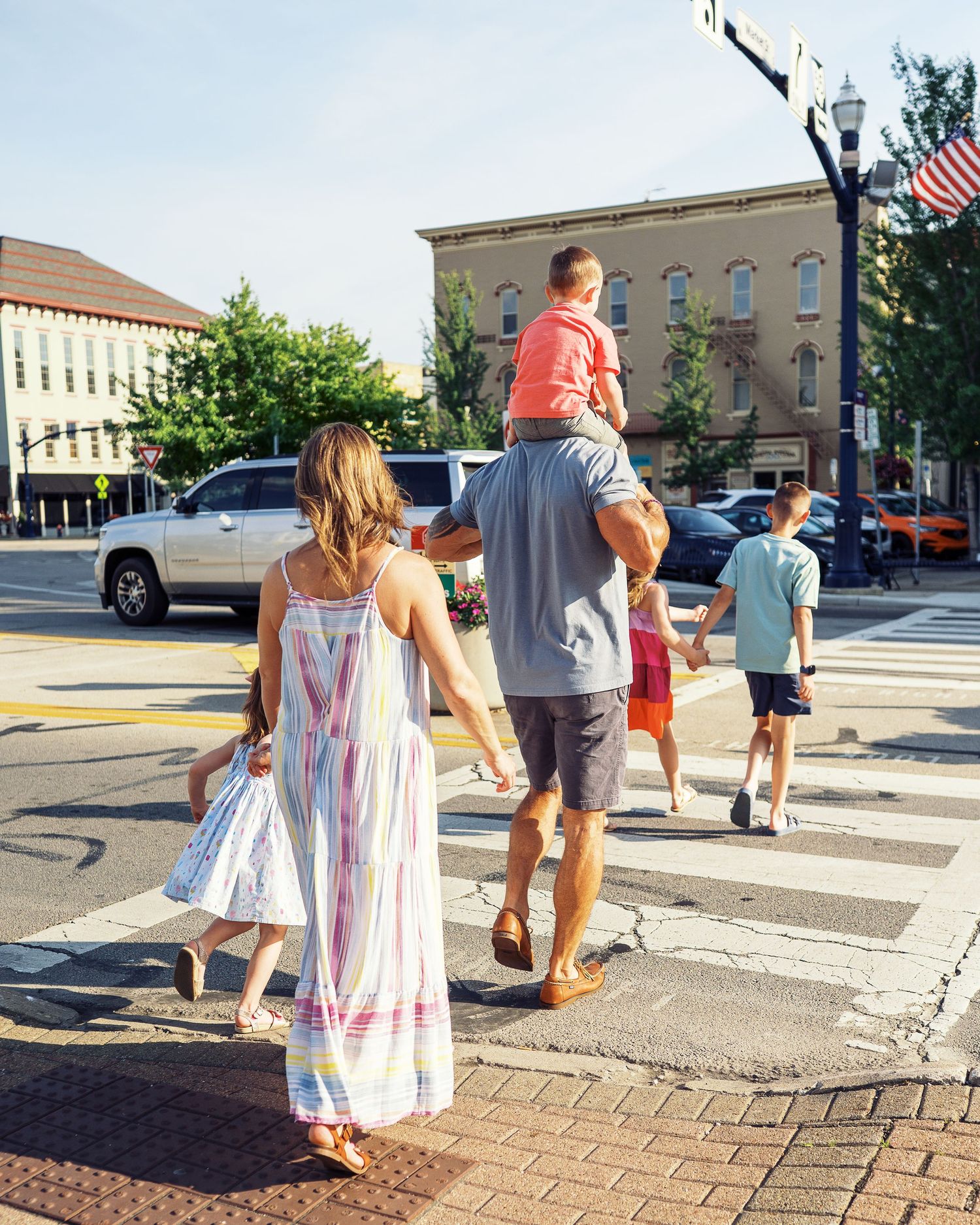 Group walking along brick sidewalk in downtown area on sunny day.