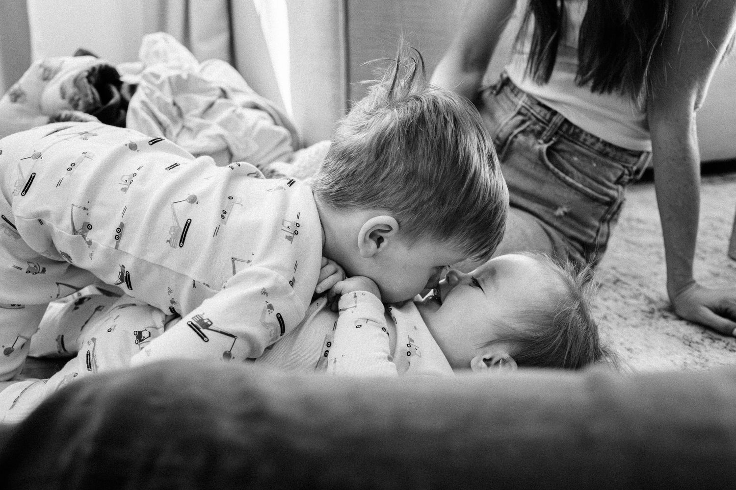 An intimate black and white photograph capturing playful moments on a comfortable couch.