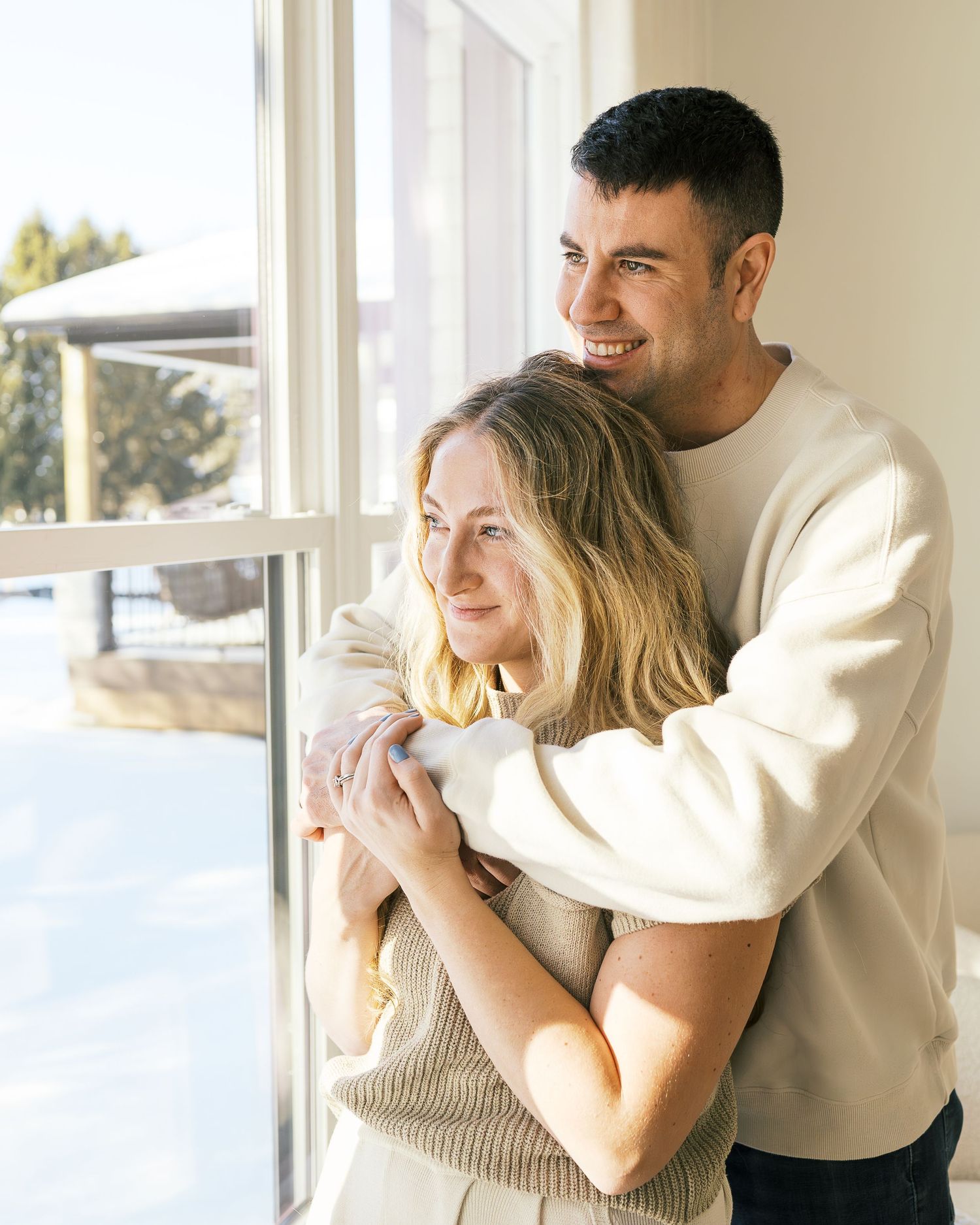 Four images showing intimate family moments in a sun-filled room with neutral decor.