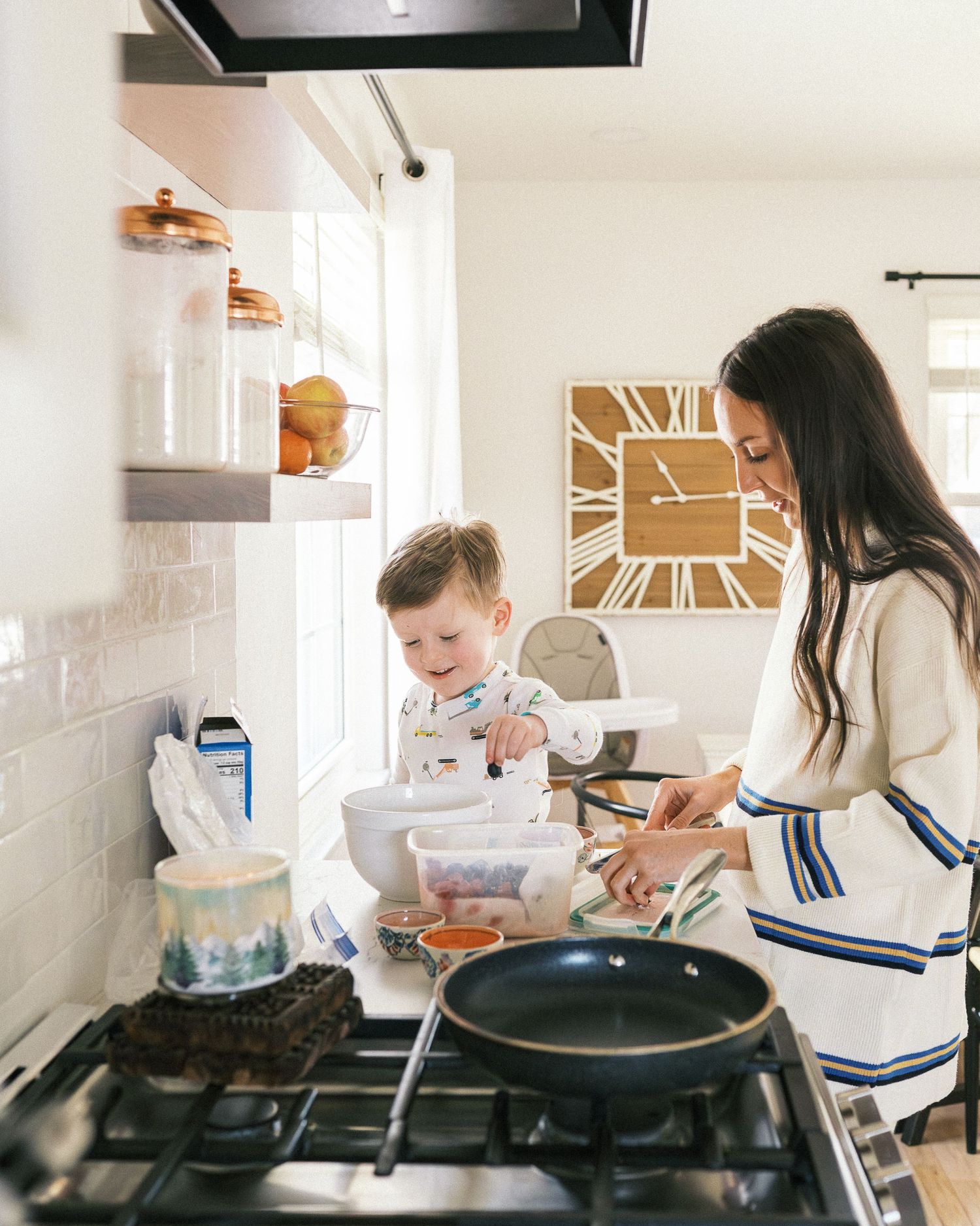 A family cooking together in a modern white kitchen with subway tile backsplash.