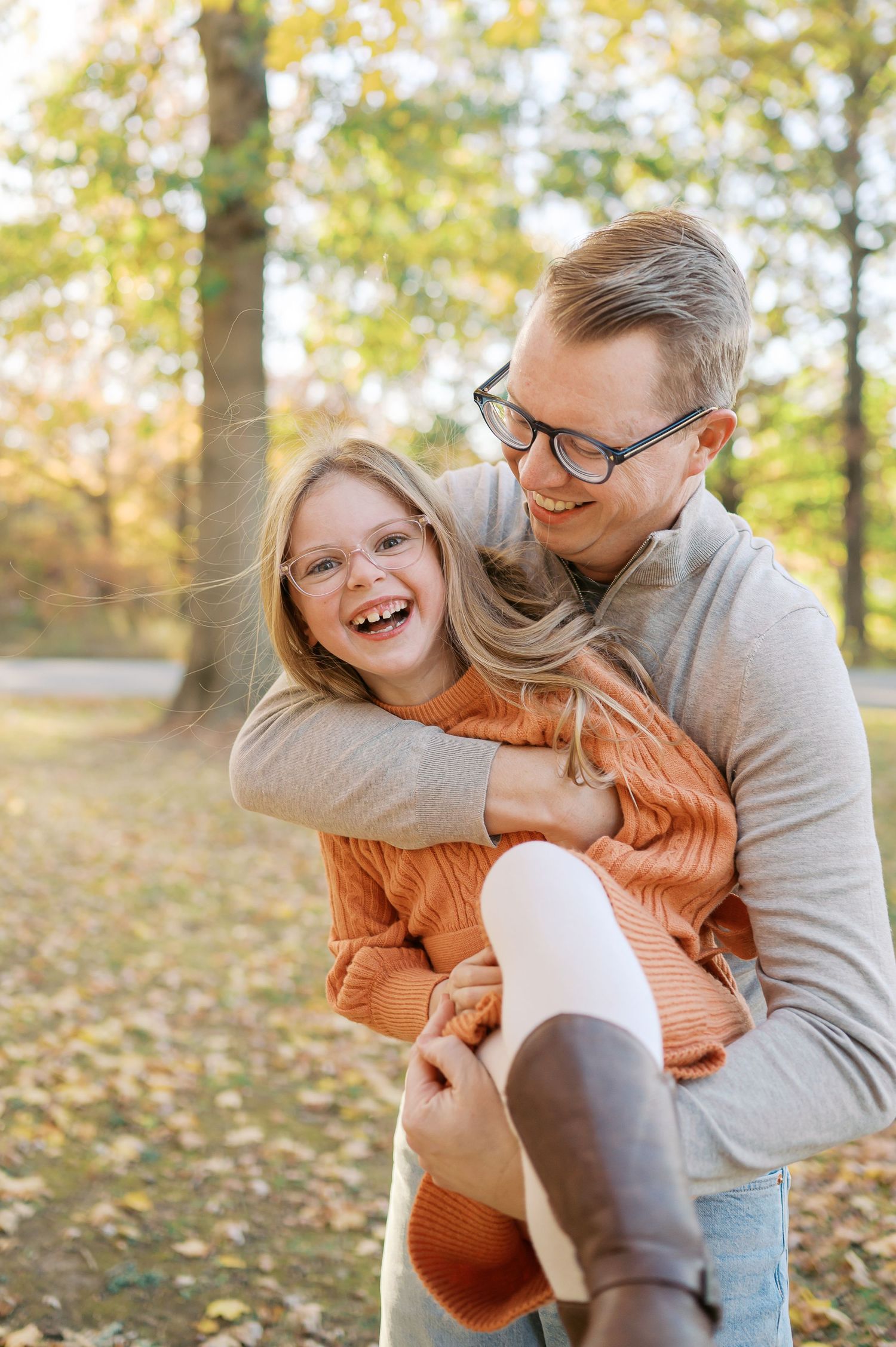Candid moments of family laughter and hugs in a fall outdoor setting.