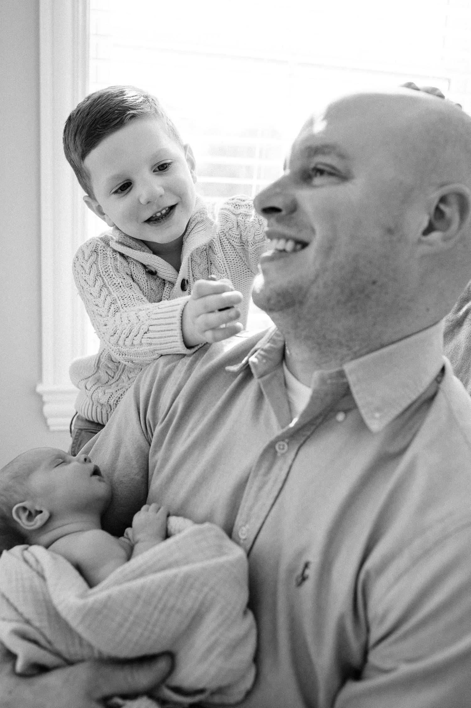 Sweet black and white candid moments showing joyful interaction between adult and baby.