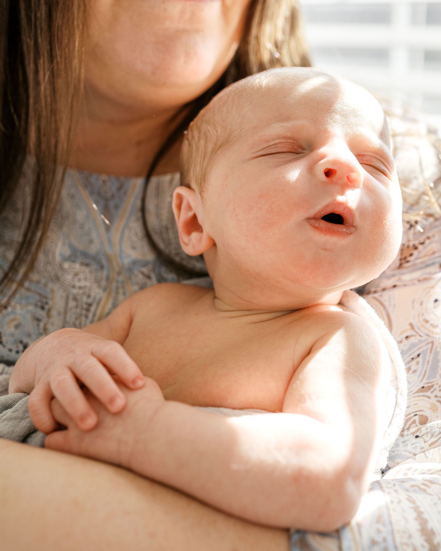Sweet close-up portraits of newborn baby being held in gentle embrace.