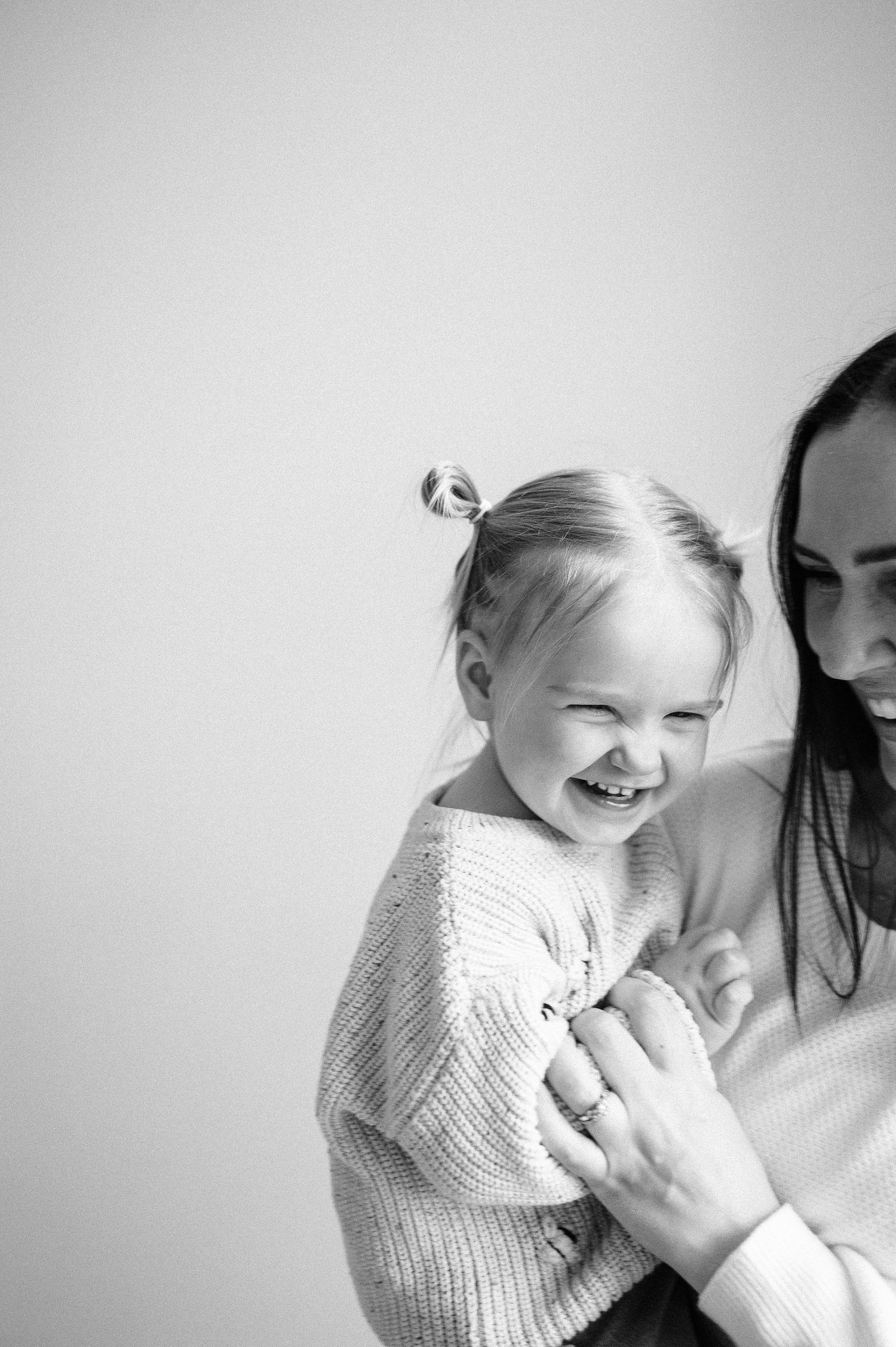 Series of high-key black and white photos showing joyful family interactions against white background.