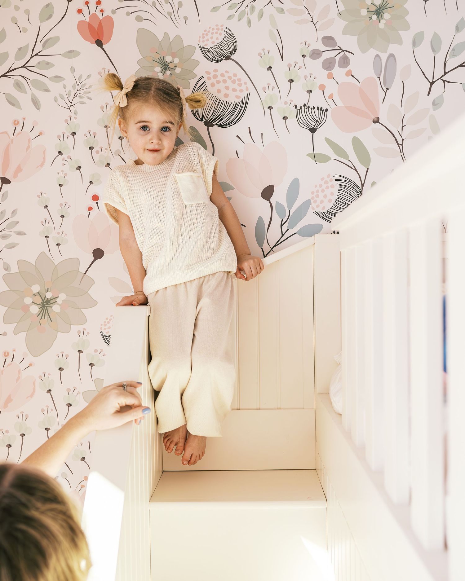 Playful interactions under floral wallpaper in white room.