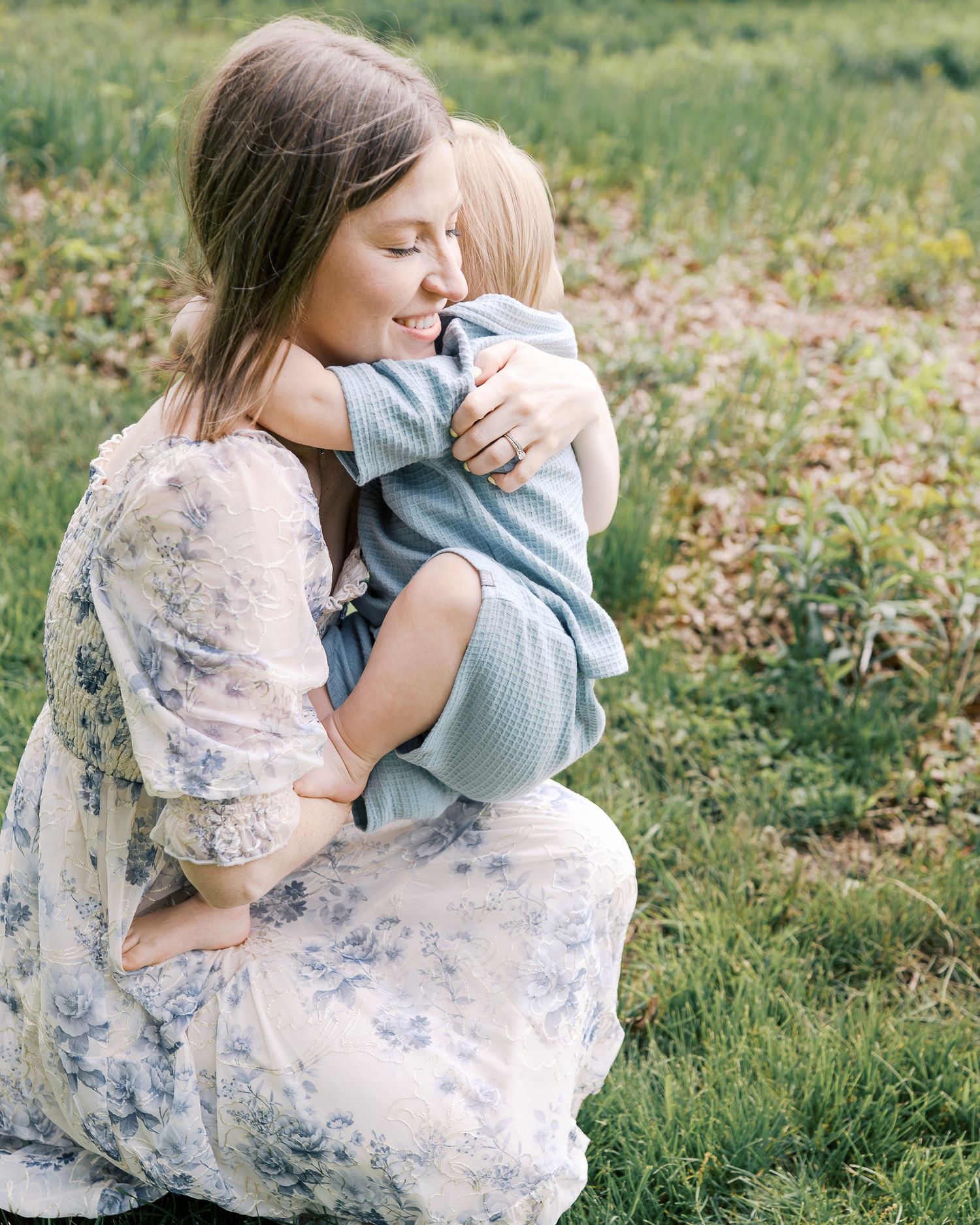 Intimate outdoor family moments captured in a sunlit meadow with floral dress details.