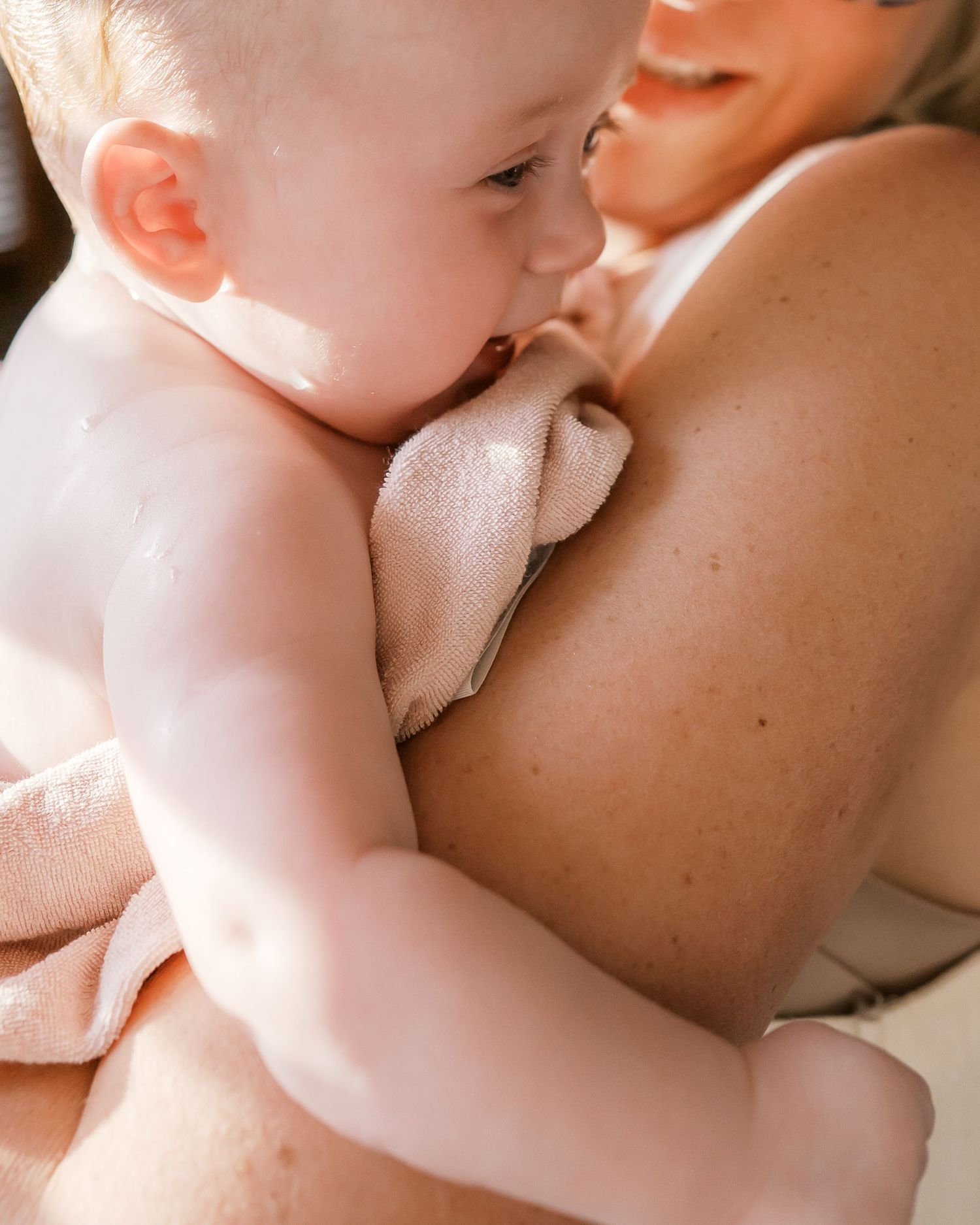 Close-up intimate moment between parent and infant in soft natural light.