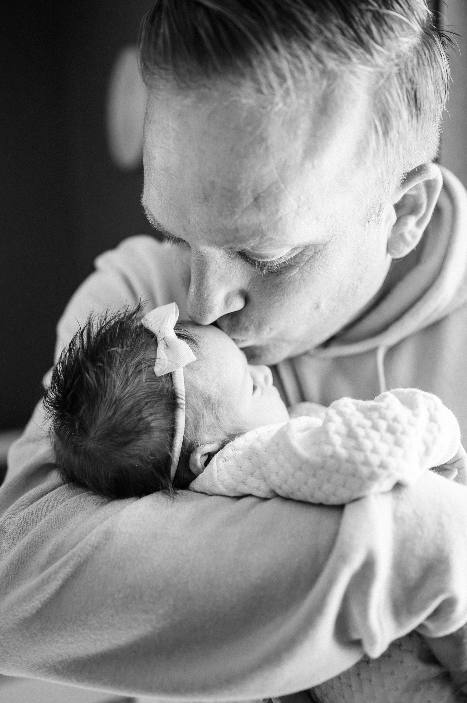 Black and white intimate portrait showing gentle care for a newborn baby.