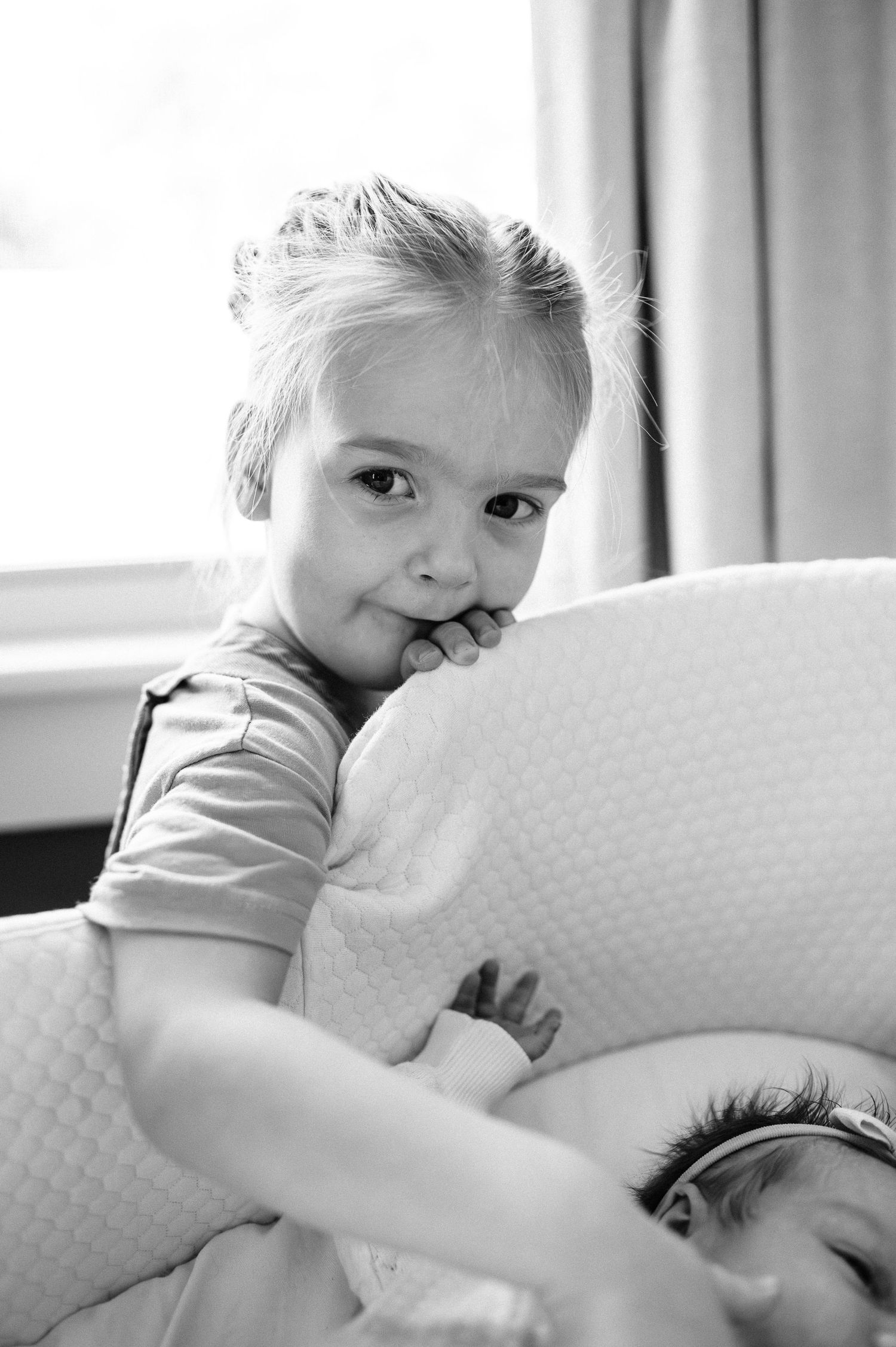 Black and white photograph of children on white cushions.