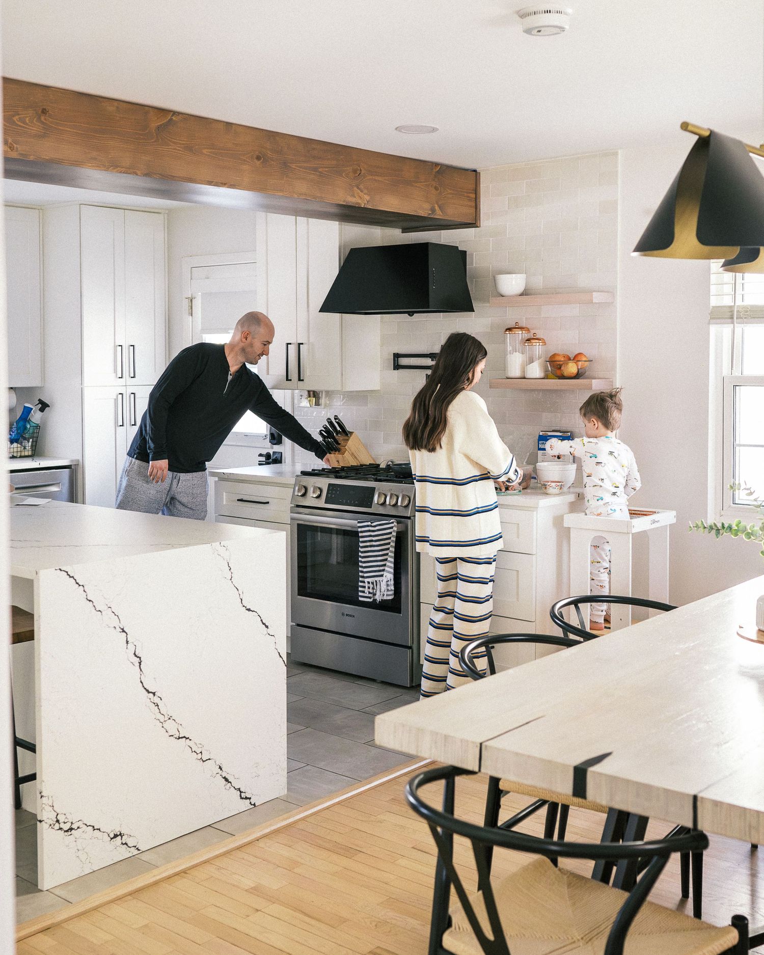 A bright modern kitchen scene with family members gathered around the counter while cooking.