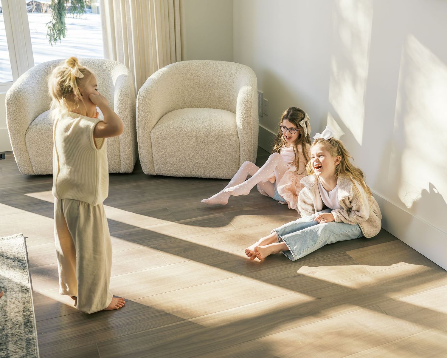 Minimalist interior scene with white furniture and sunlight casting shadows.