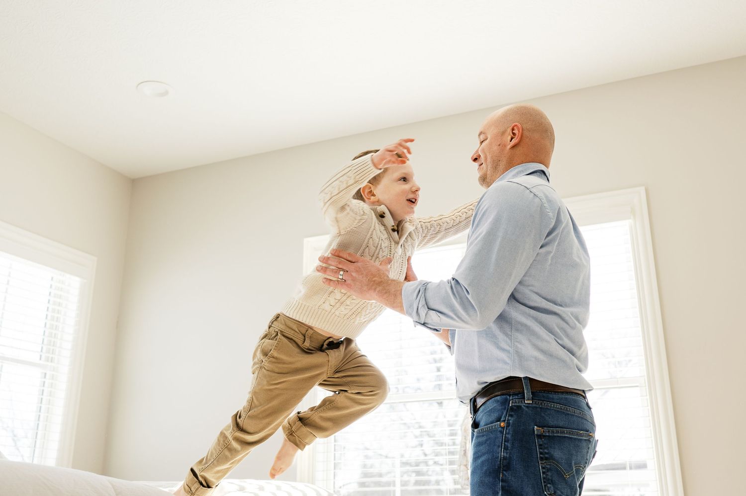 A joyful moment as a child is lifted high into the air indoors.