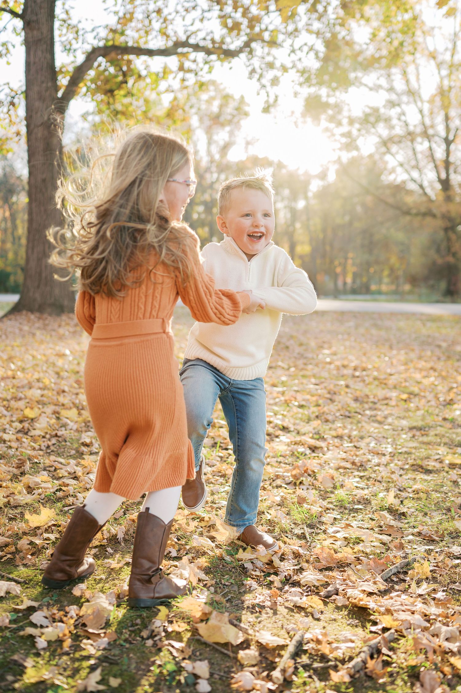 Playful running through autumn leaves captured in warm evening sunlight.