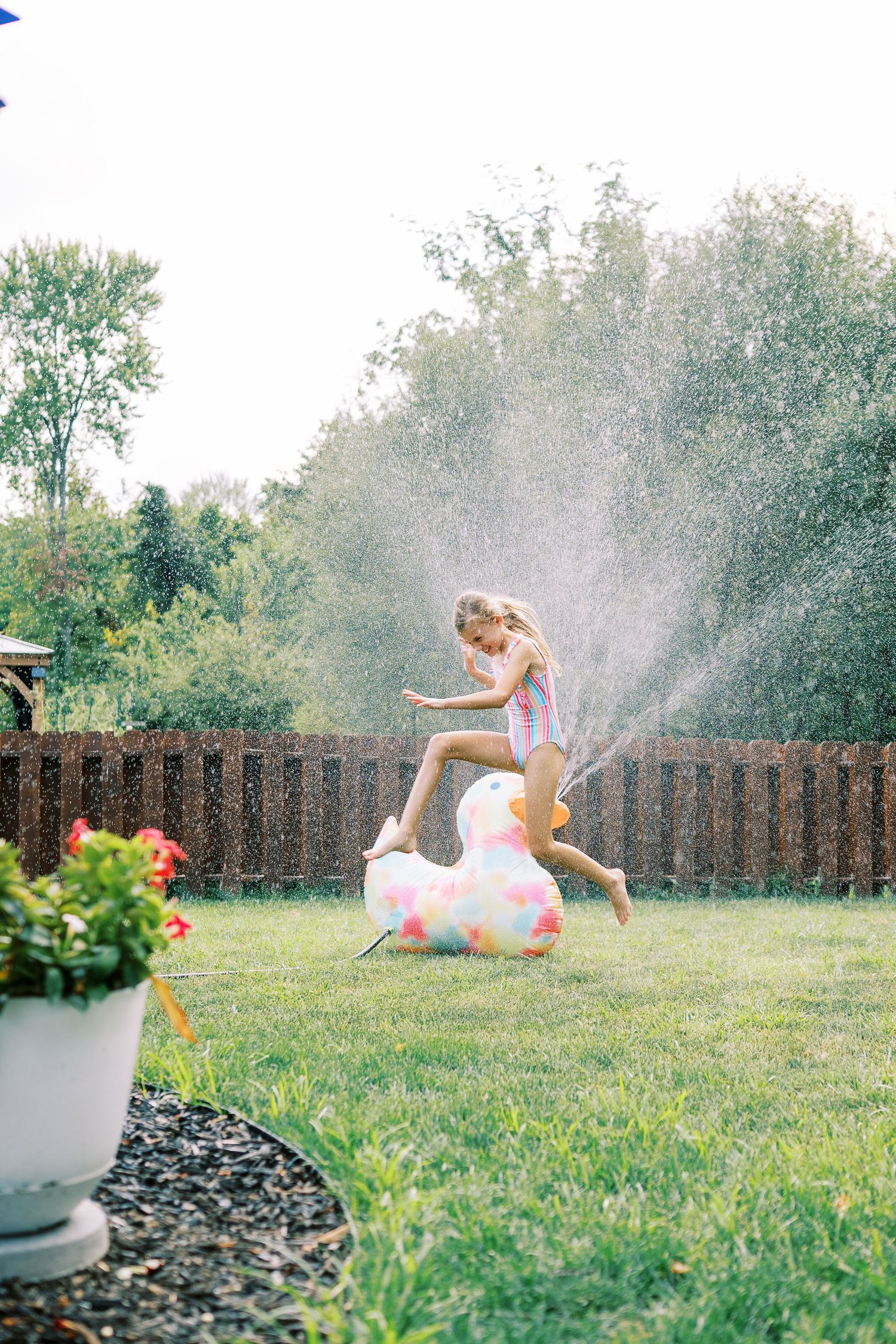 Kids playing in lawn sprinkler on a sunny summer day.