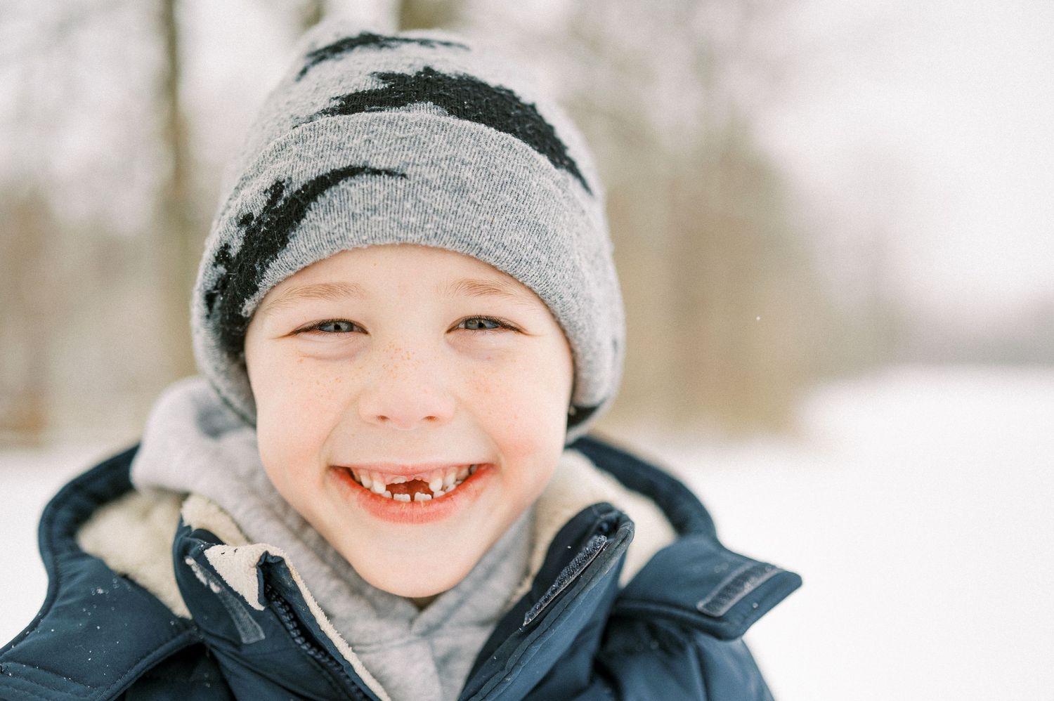 Winter portrait of someone wearing a cozy knit hat and warm jacket in the snow.