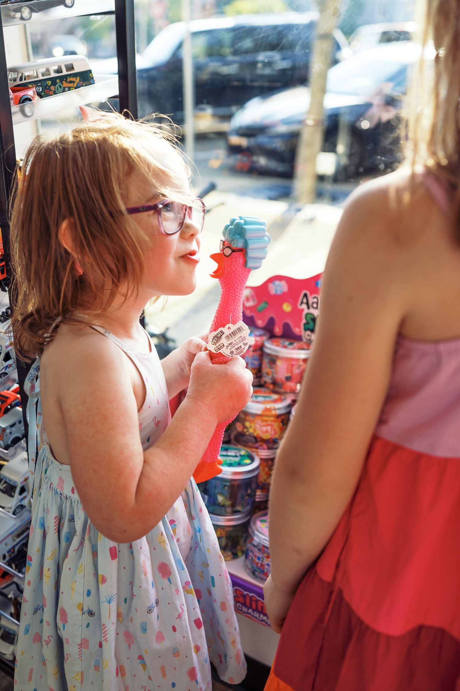 Child wearing glasses looks at treats in store display case.