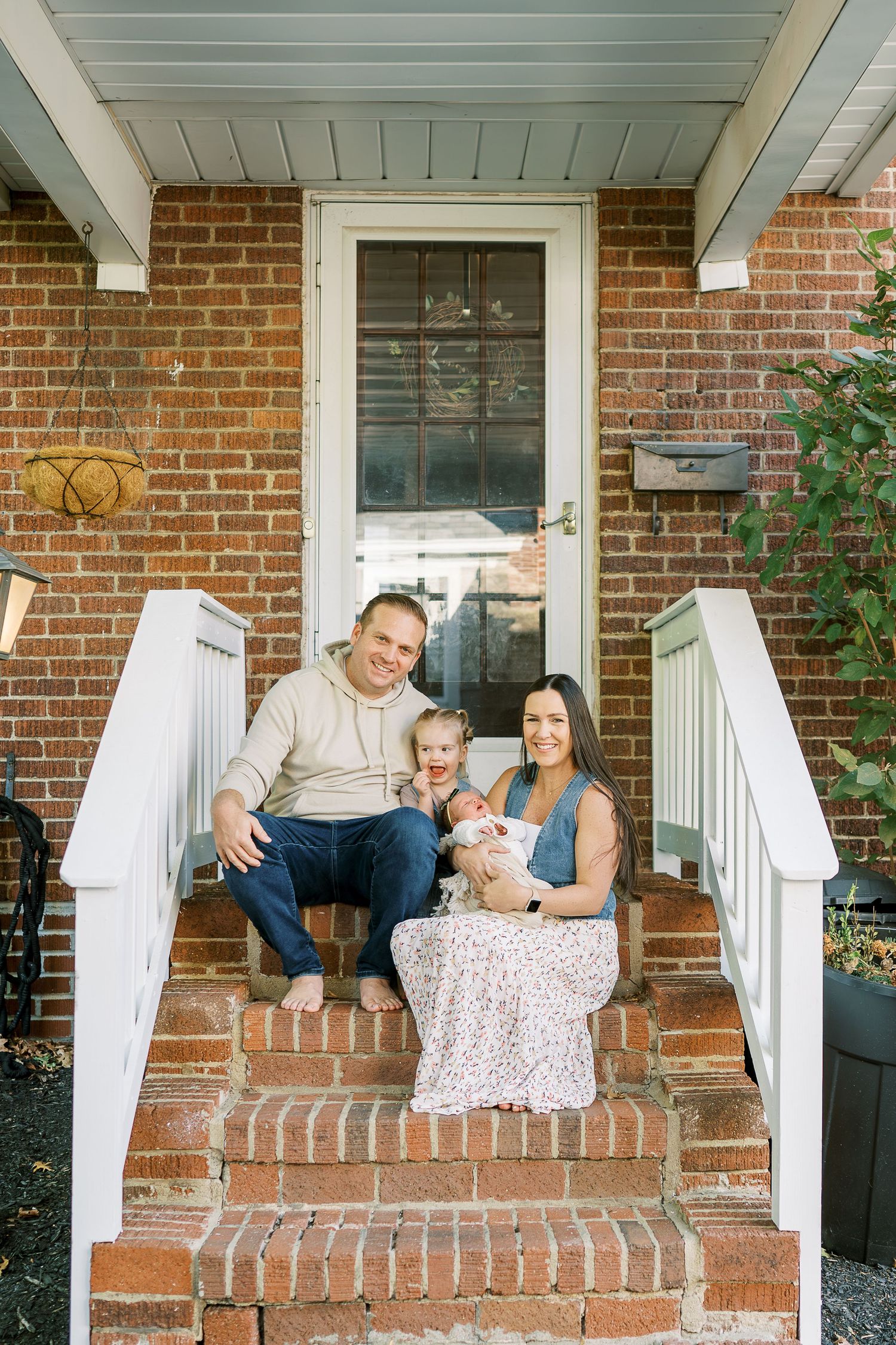 Family shares candid moments together on their brick front porch during a photo session.