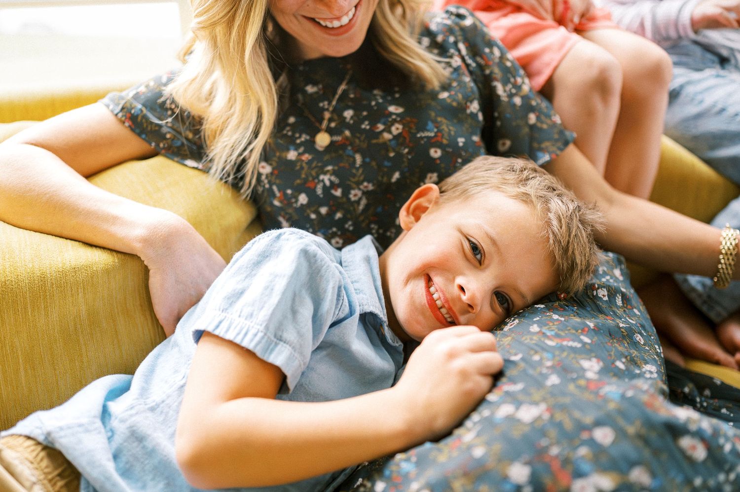 Playful cuddle time between family members on a sunny couch.