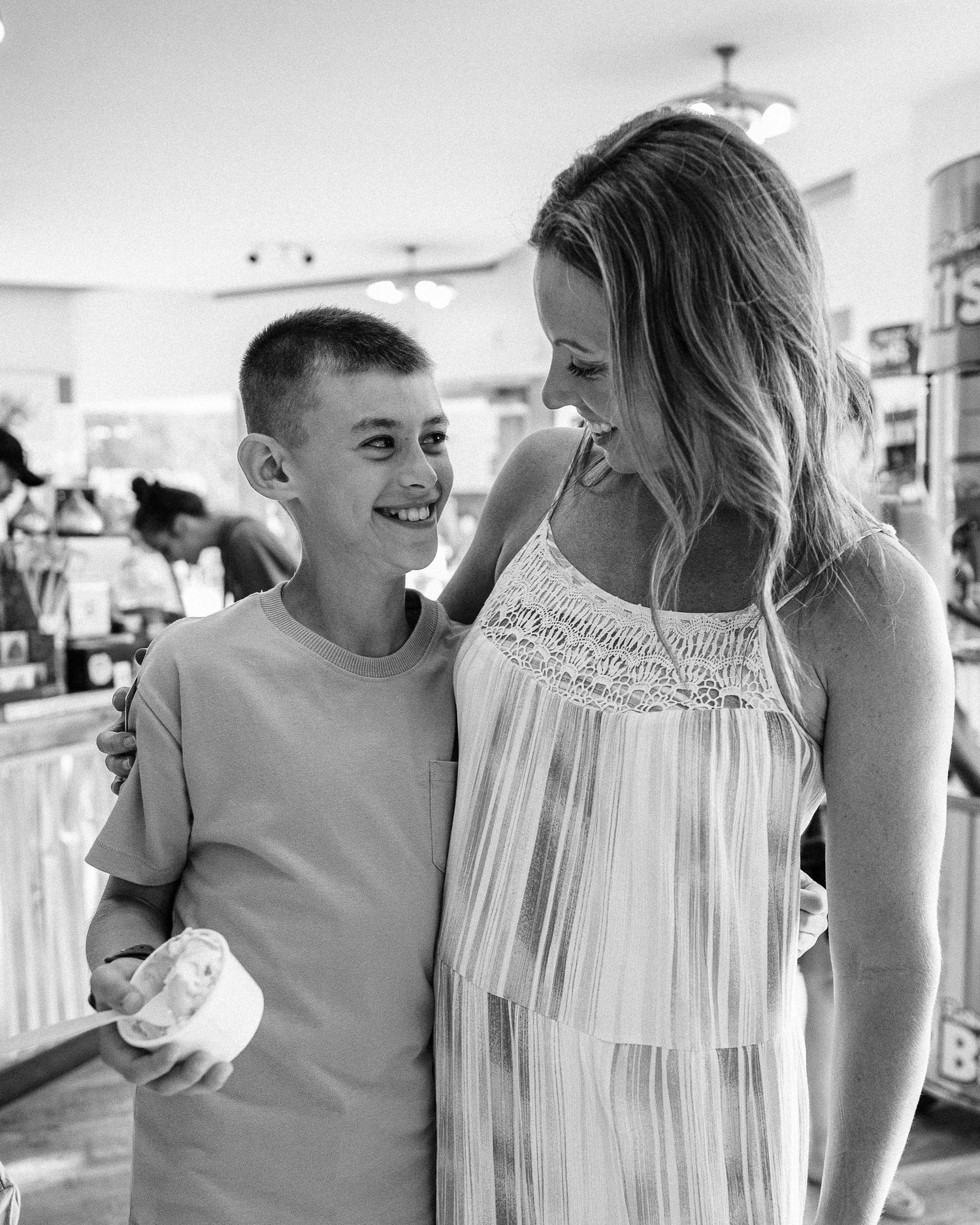 Black and white portrait of two people sharing a joyful moment at an ice cream shop.