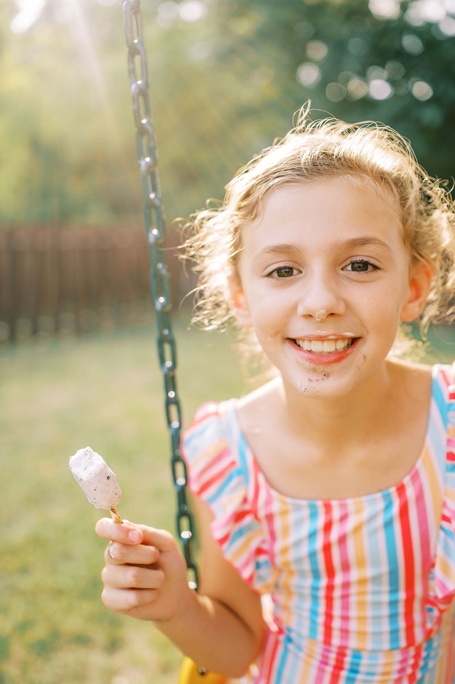 A summer day captured with a striped dress and ice cream cone by the swing set.