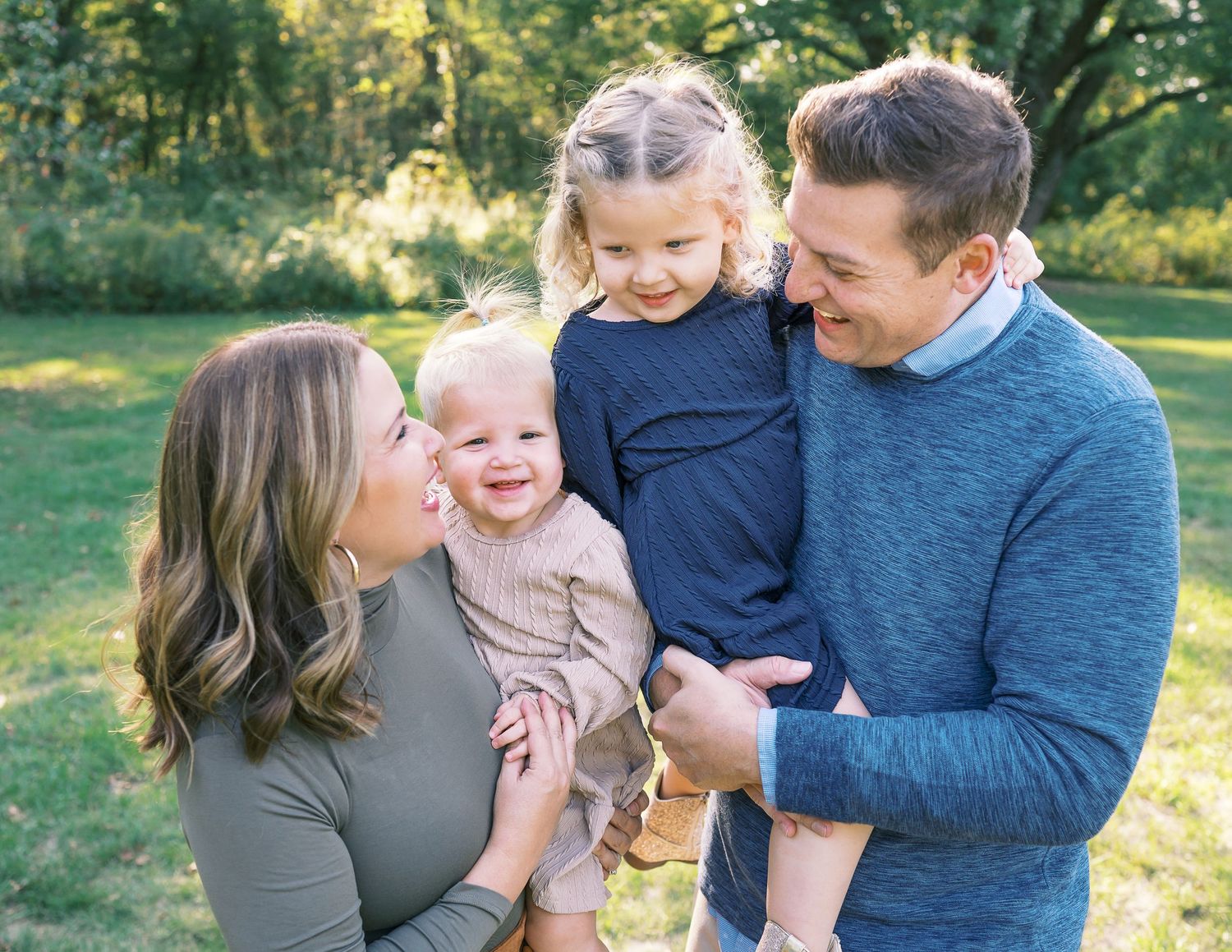 Family enjoying a tender moment together outdoors during golden hour in a park setting.