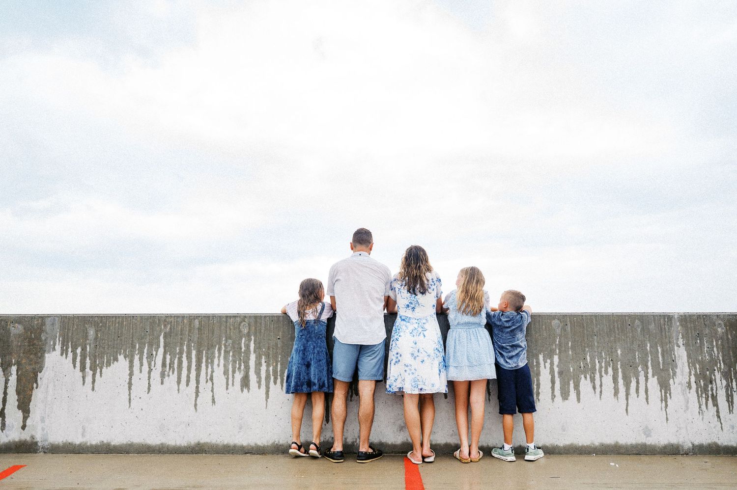 A family group huddles together on a boardwalk overlooking a scenic beach vista.