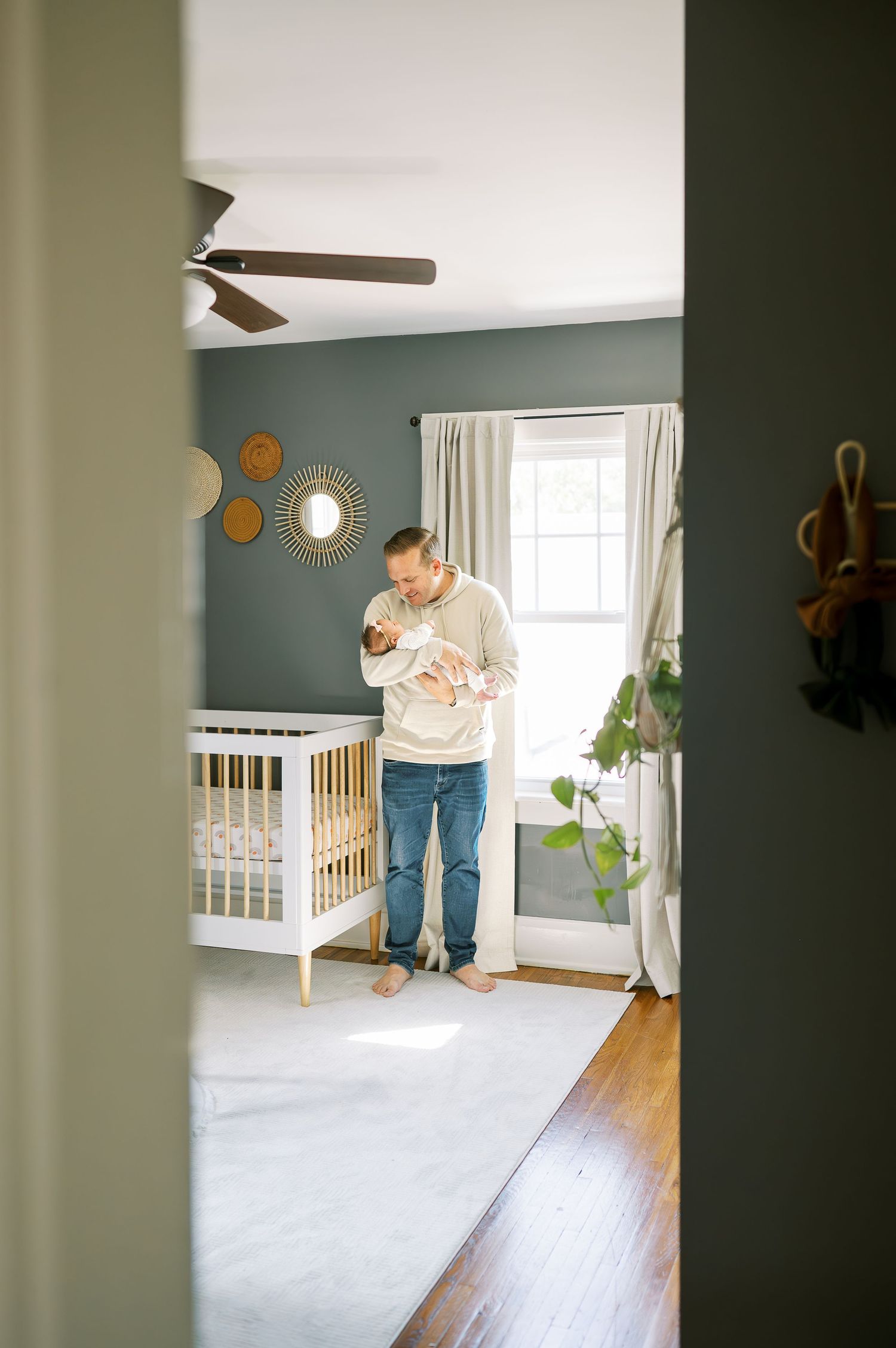 Peaceful nursery scene viewed through doorway with crib and warm lighting.