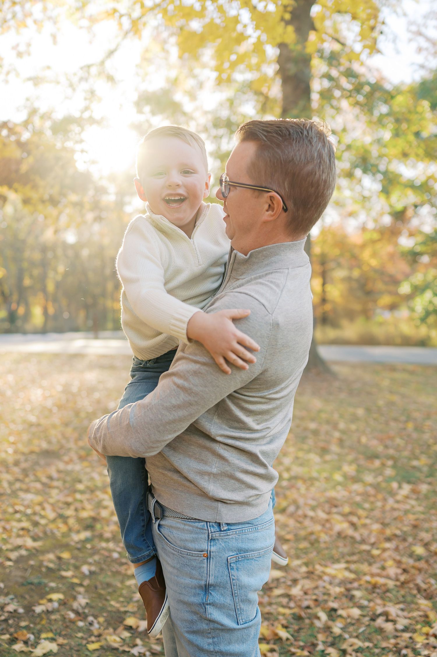 Sweet moment between parent and child playing in a sunlit autumn park setting.