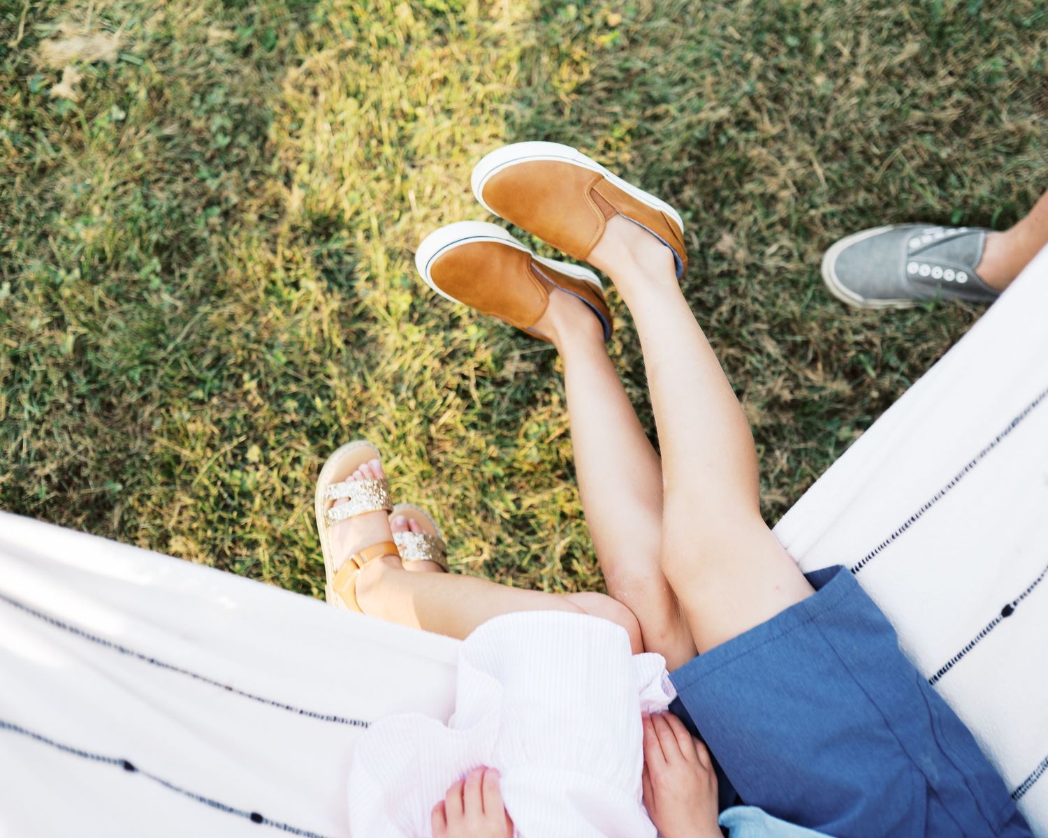 Family members relax together on grass in a sunlit outdoor setting.