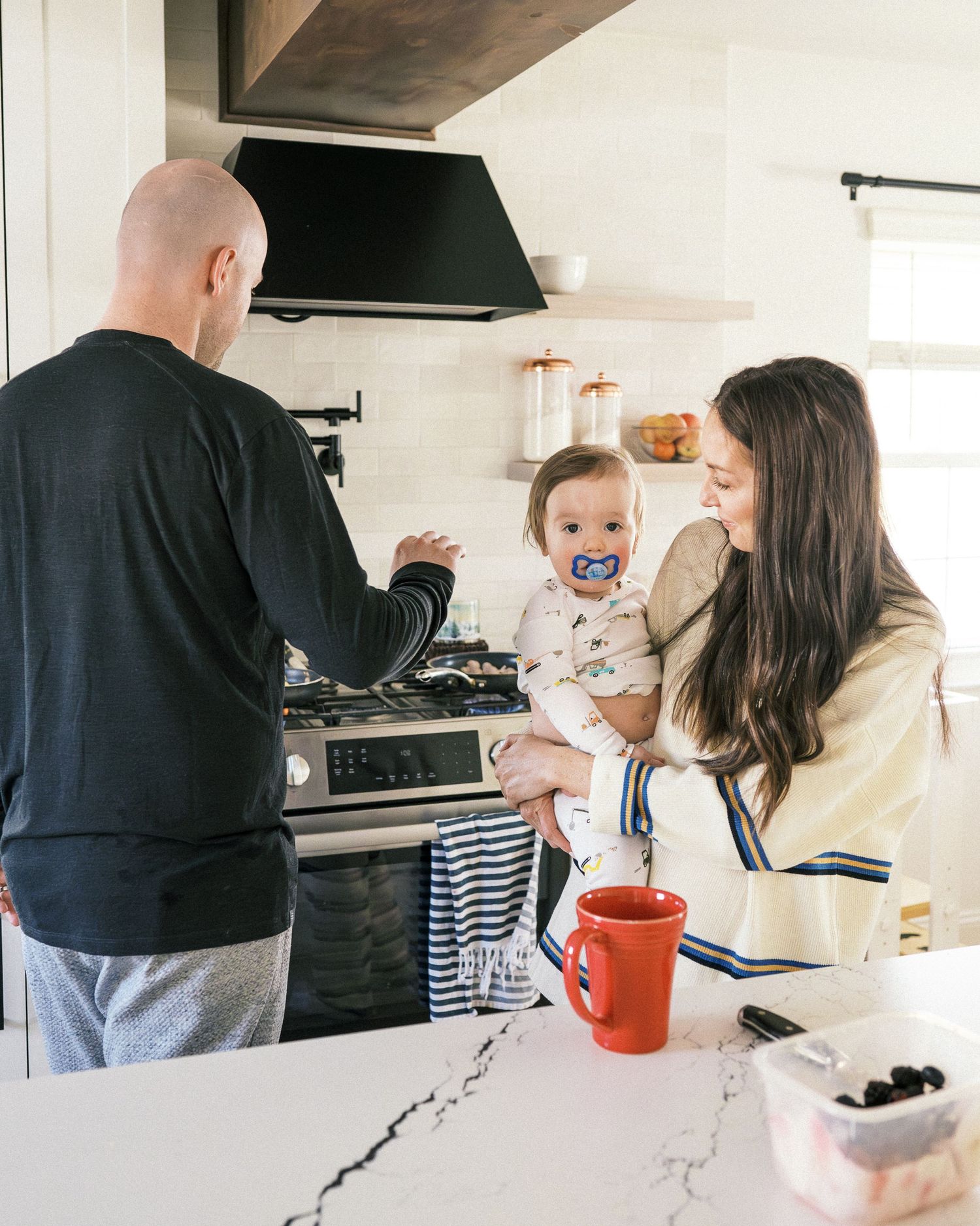 Family cooking together in a modern white kitchen with marble countertops.