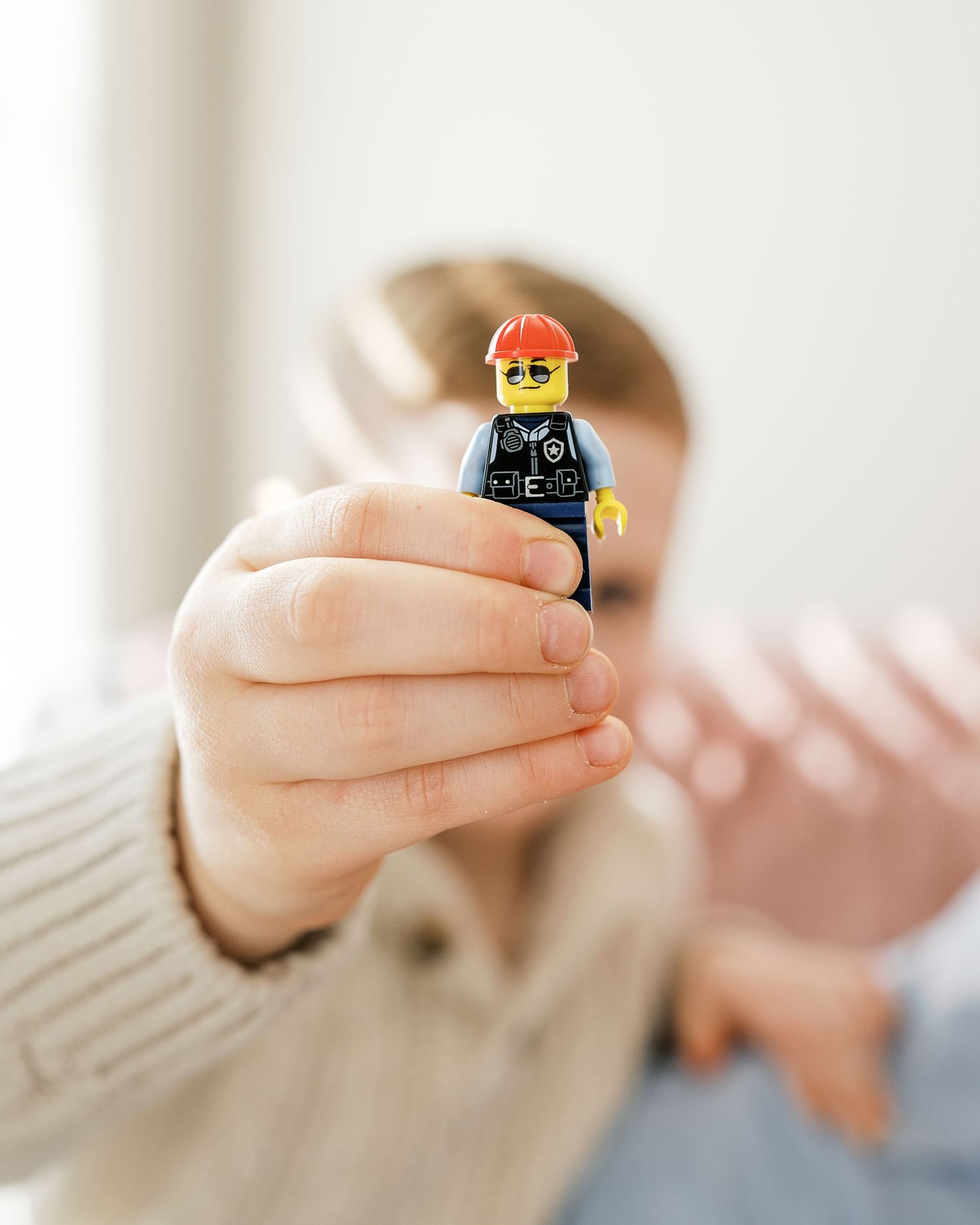 Hands holding small LEGO minifigures in close-up detail shots.