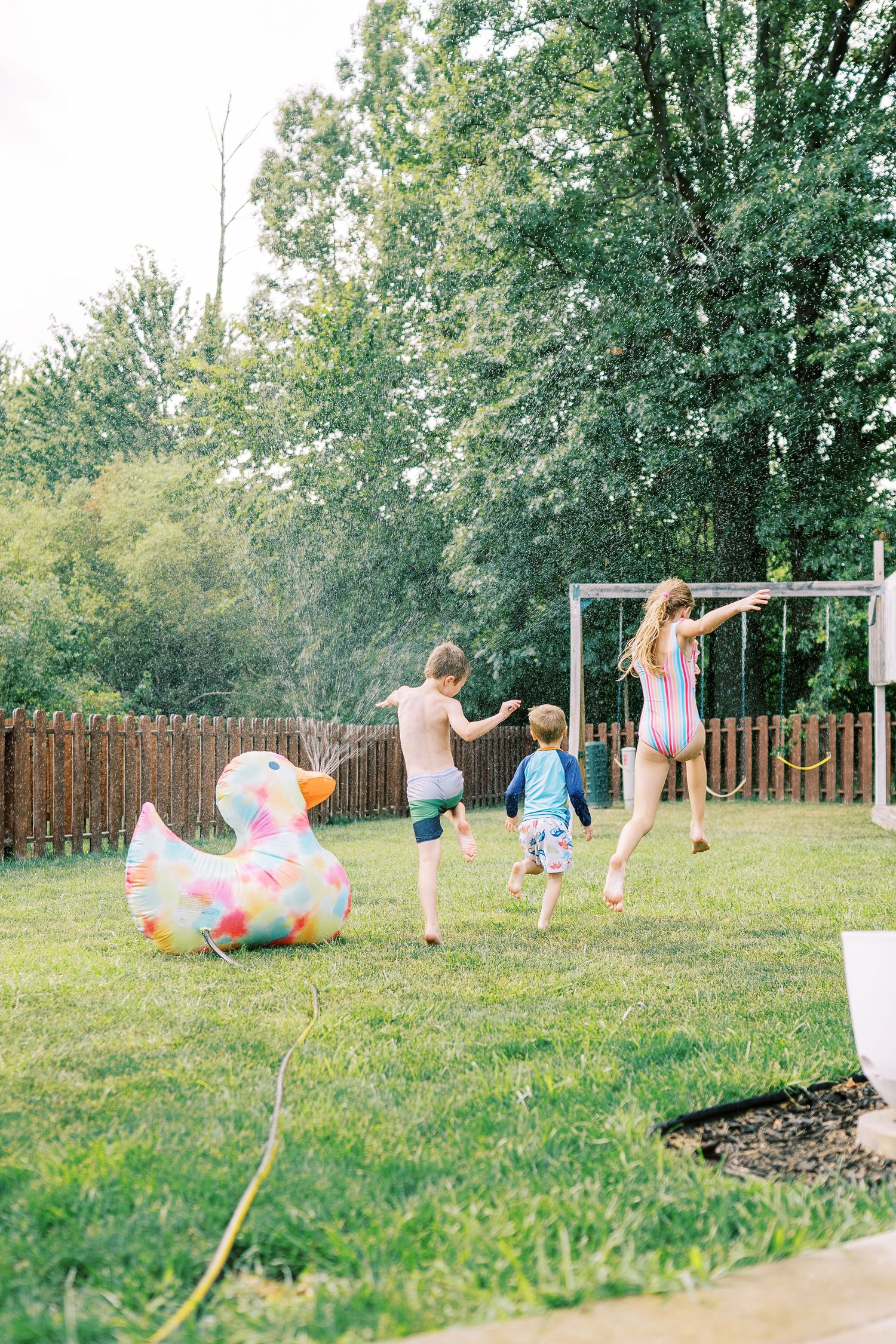 Summer fun in the backyard with a colorful inflatable unicorn float and sprinkler play on a sunny afternoon.