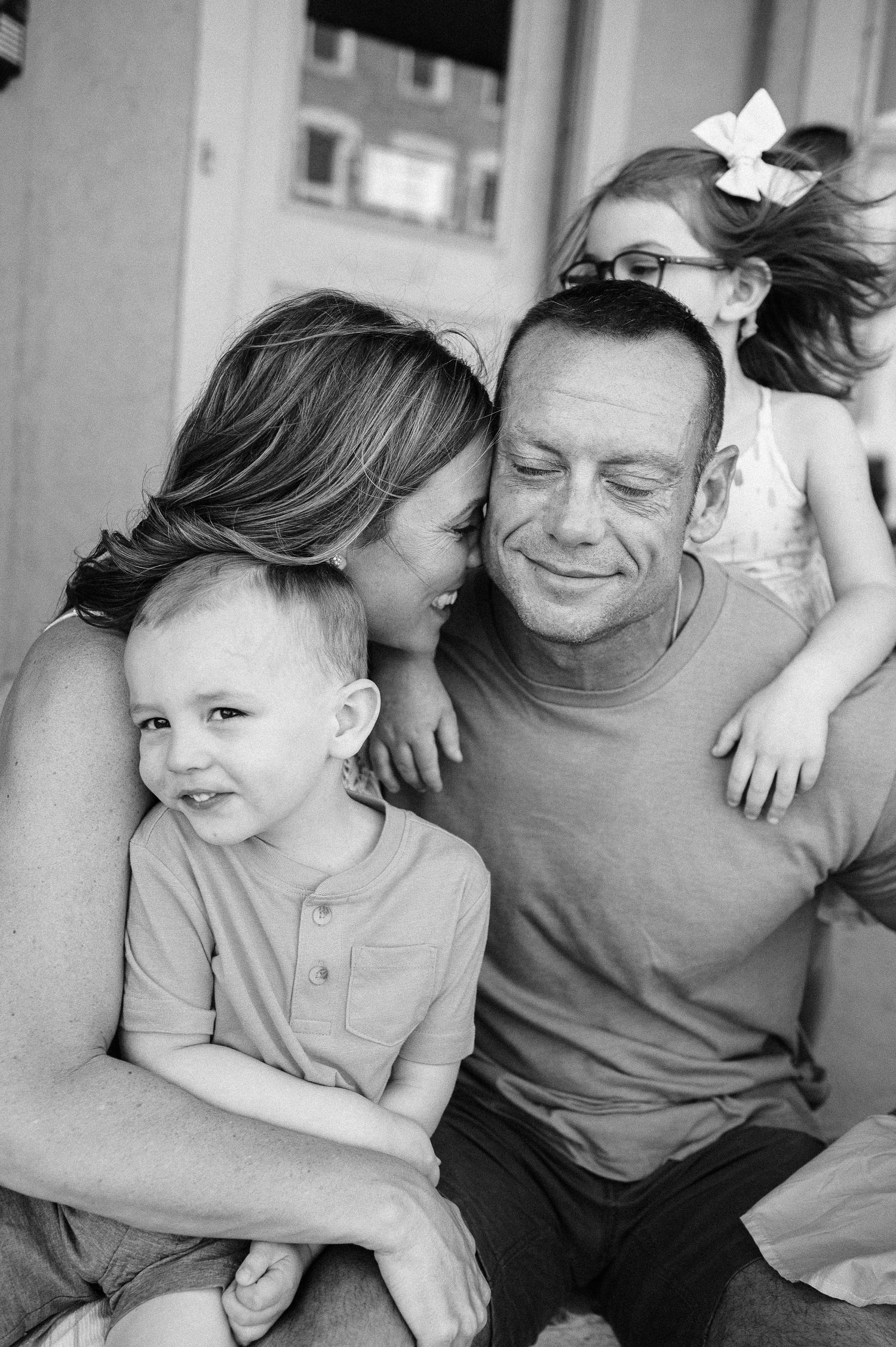 A black and white portrait capturing an intimate family moment outdoors.