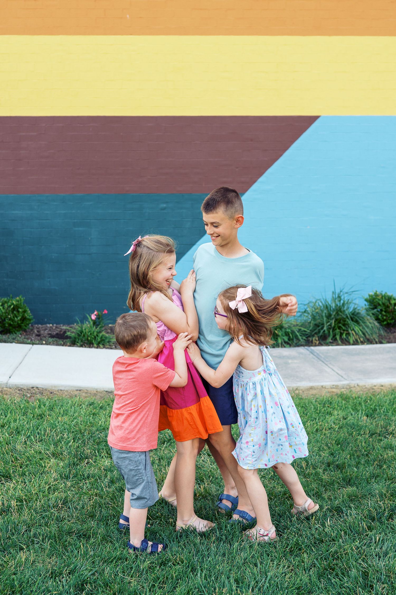Children engage in energetic play against a multicolored wall backdrop in an outdoor setting.