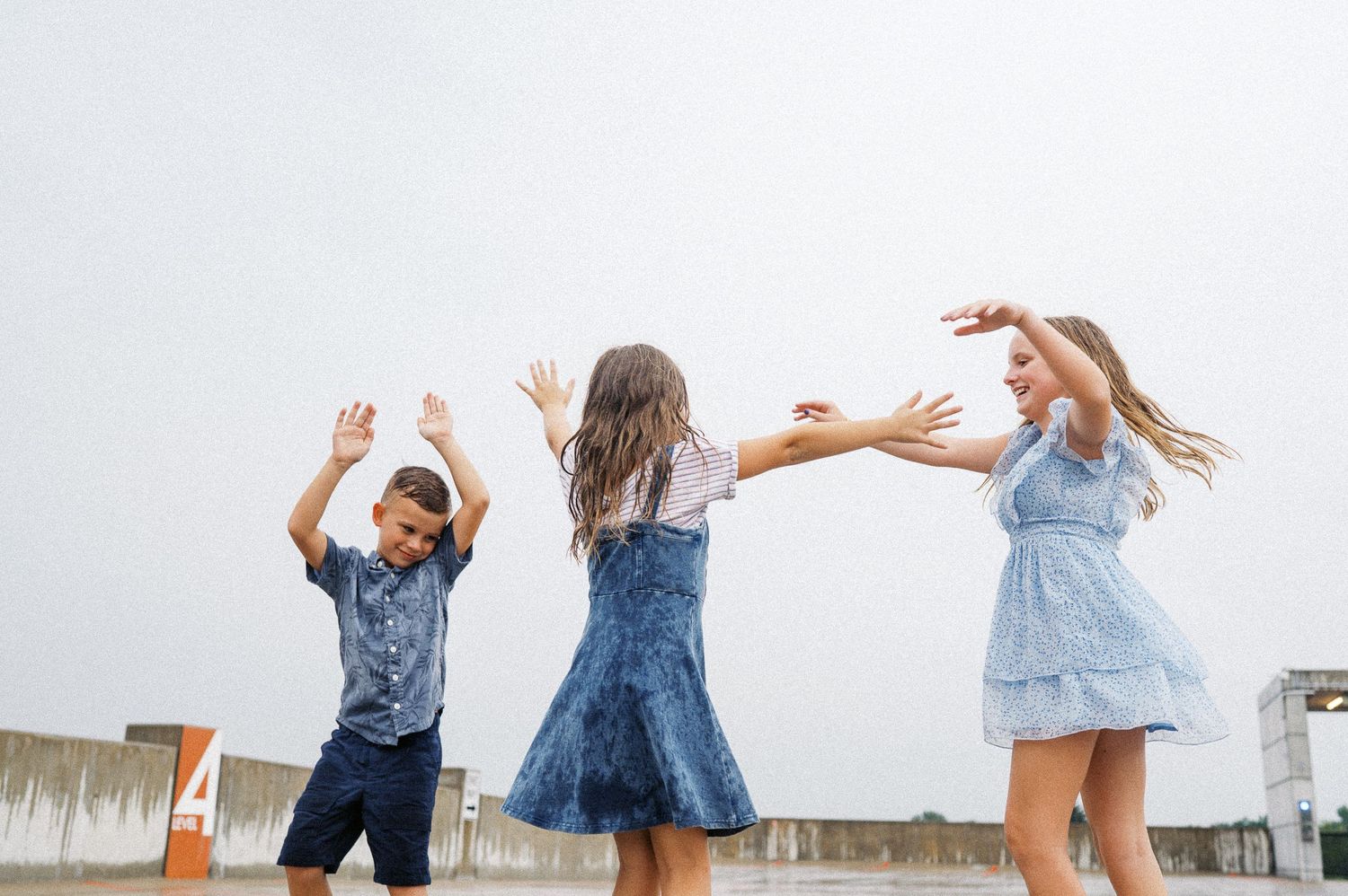 Children jumping and playing together on a rooftop dressed in coordinating blue outfits.