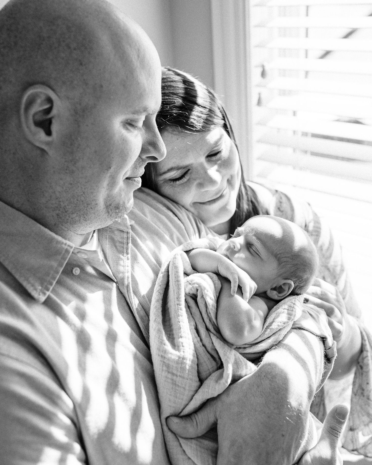 Natural light portraits capturing tender moments between parent and newborn.