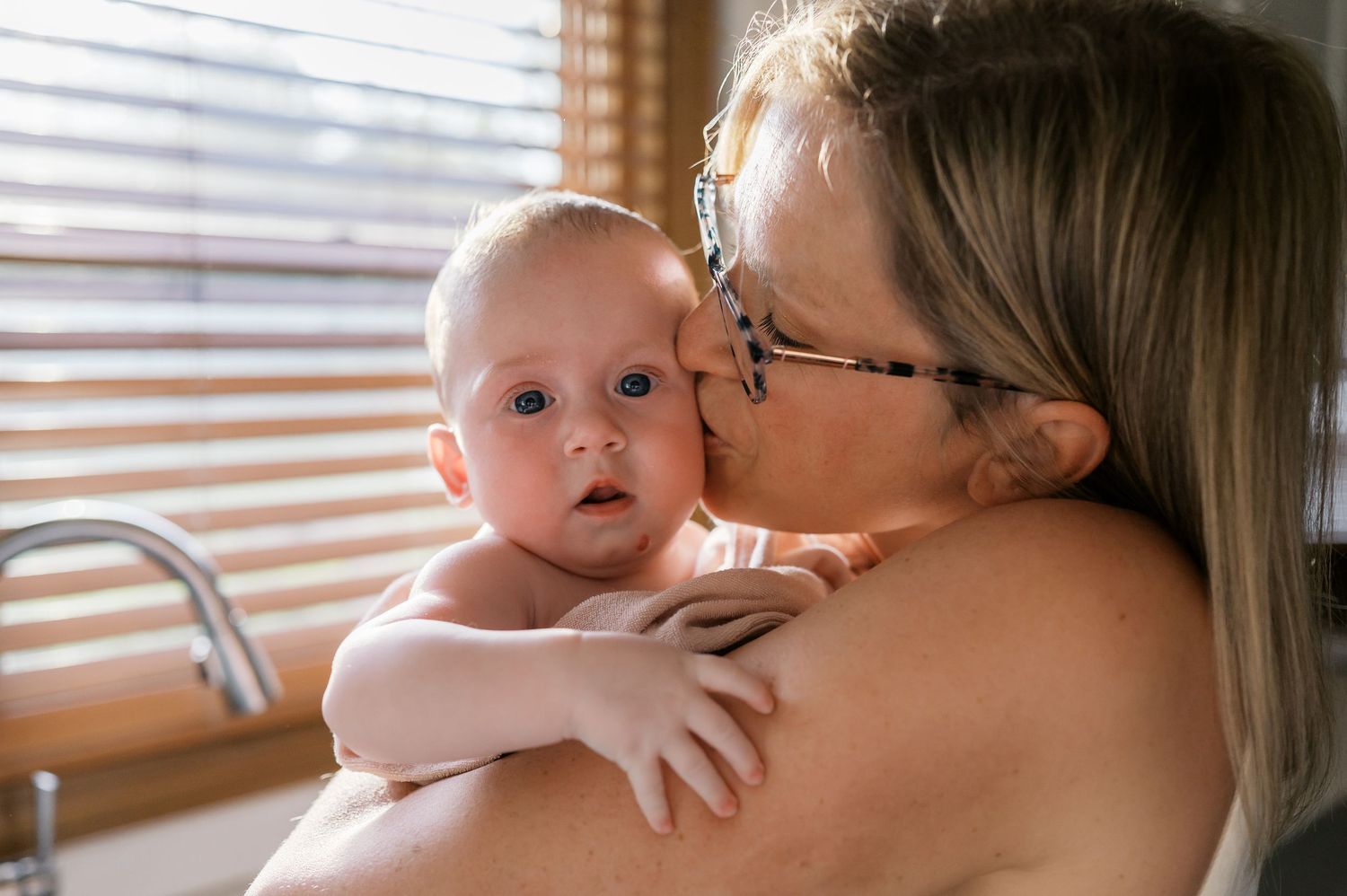 Tender moment captured by a window in warm natural lighting.