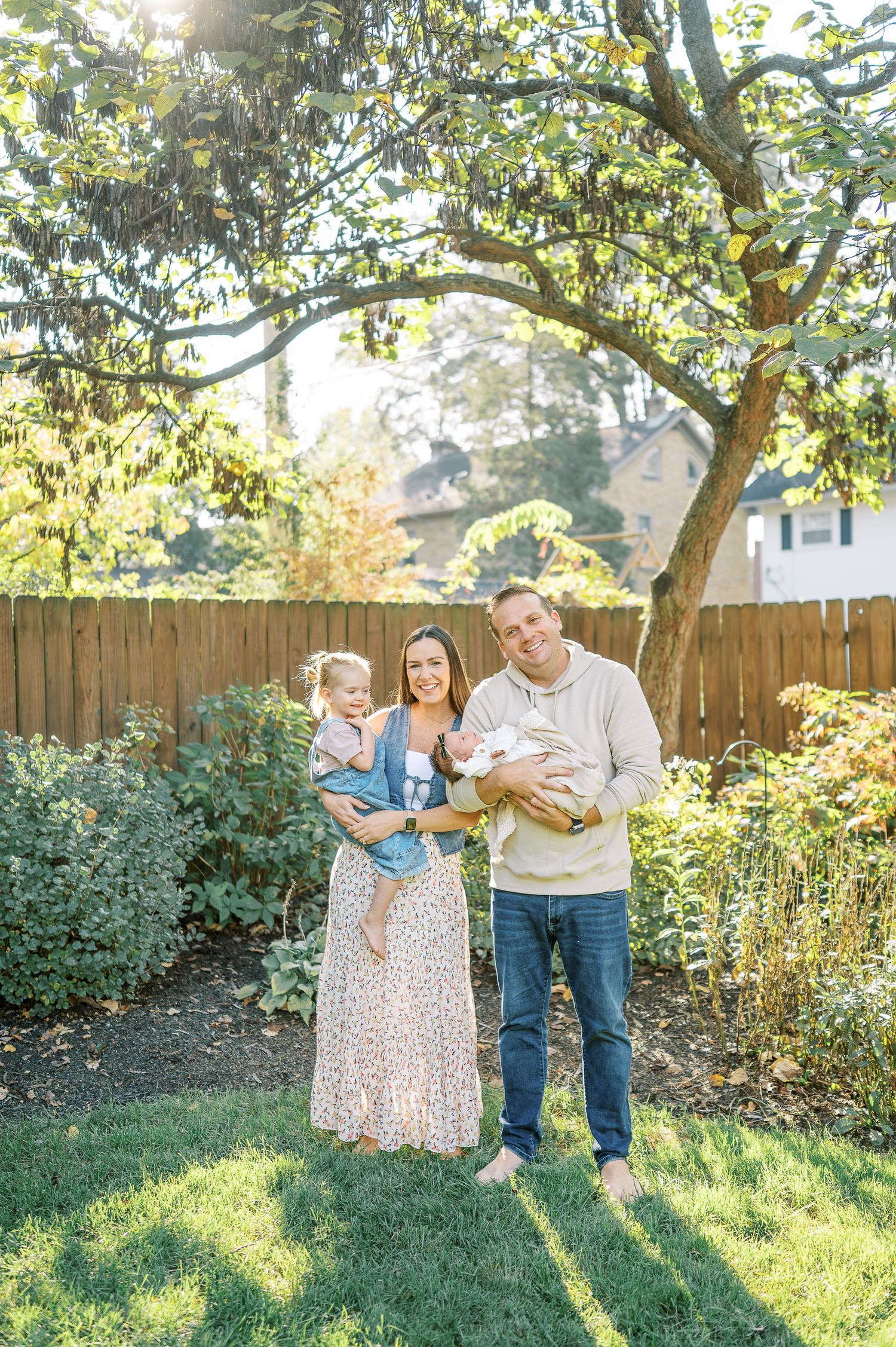 A happy family shares tender moments together in their backyard with natural sunlight filtering through trees.