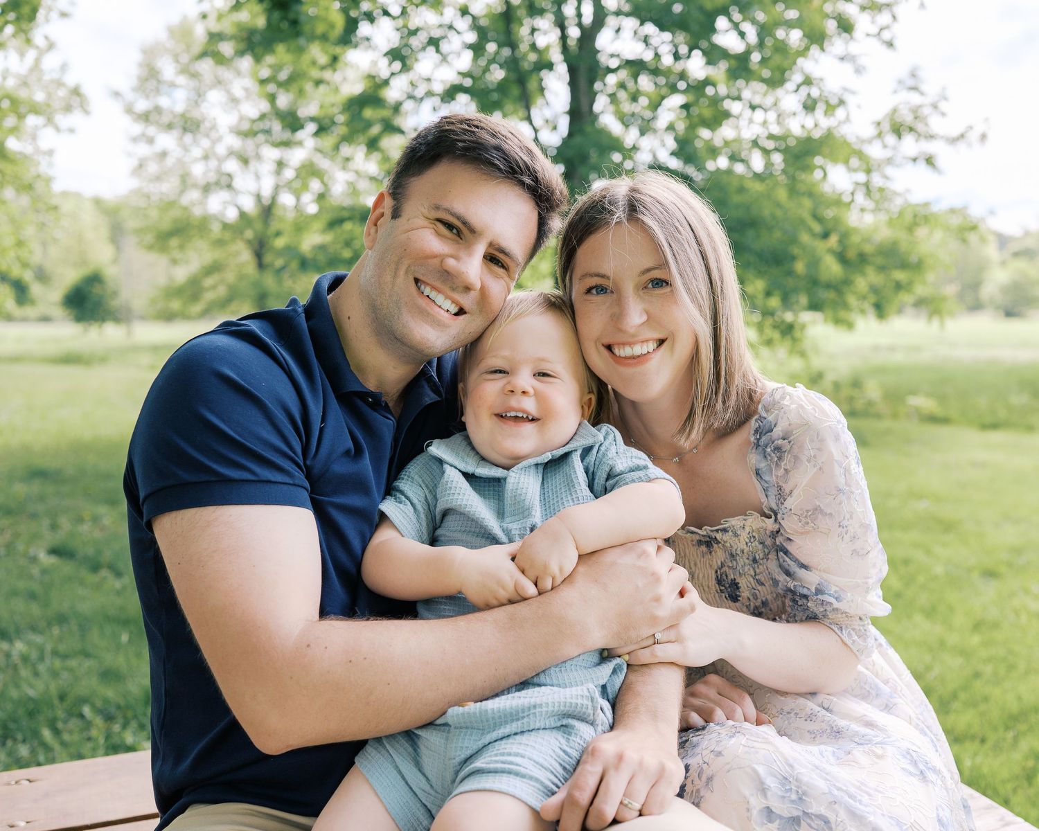 Family sitting together on grass during outdoor photo session.
